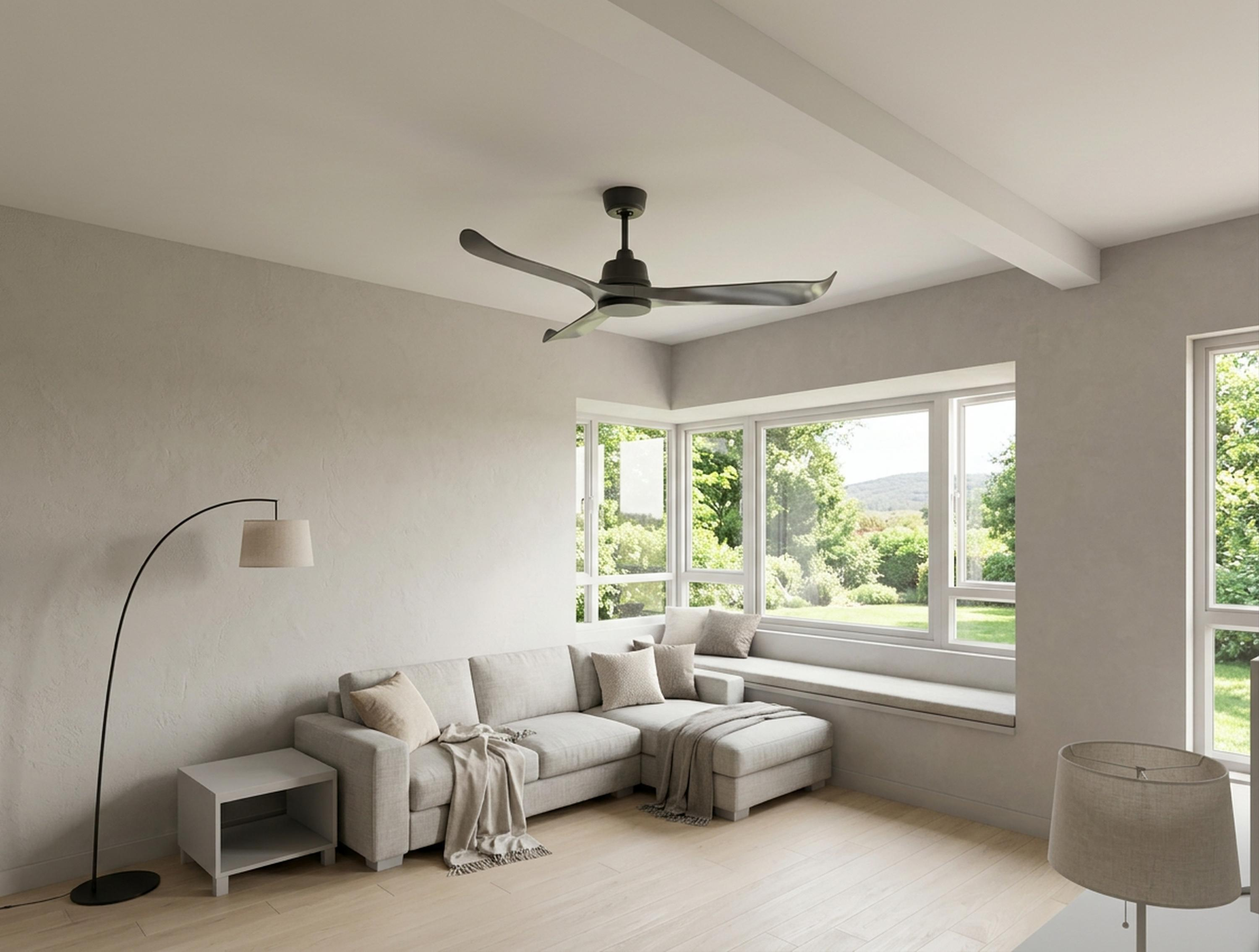 Una sala de estar con sofá, ventilador de techo y grandes ventanales con vistas a la vegetación.