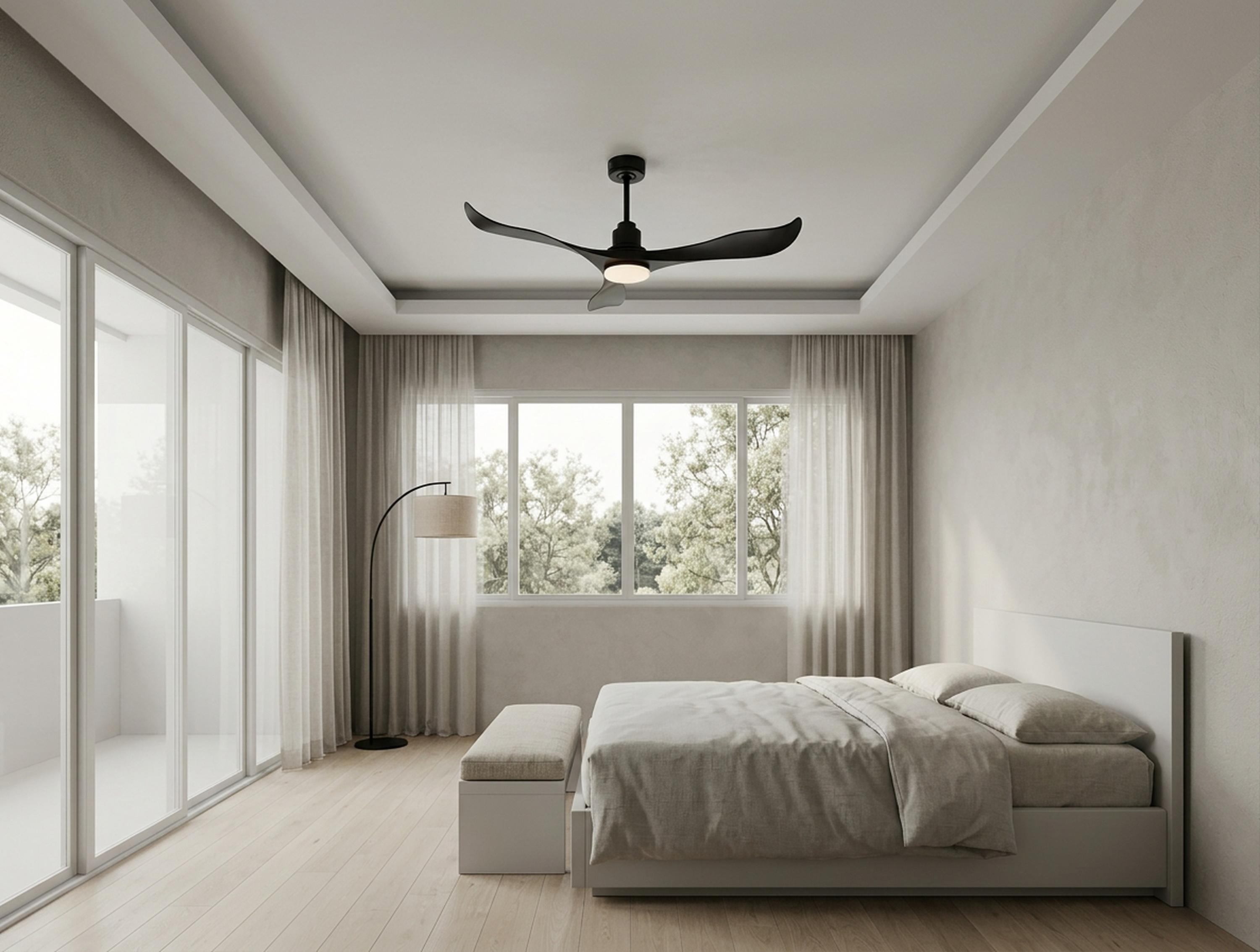 Dormitorio moderno con cama, ventilador de techo y puerta balcón con vistas a la vegetación.