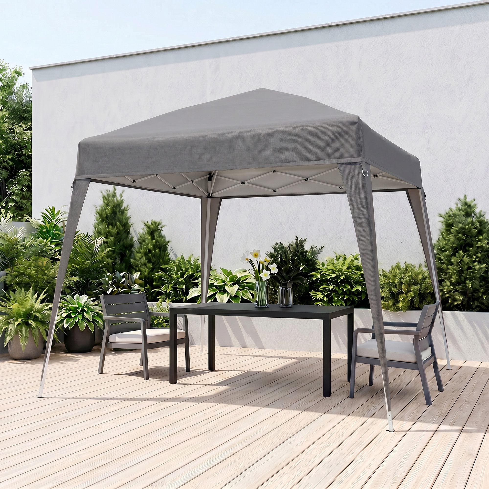 Gazebo gris con mesa y sillas en terraza de madera, rodeado de plantas.