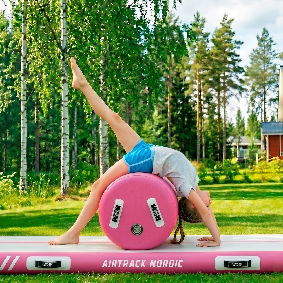 Dziewczynka robi mostek na różowym airtracku na zewnątrz.