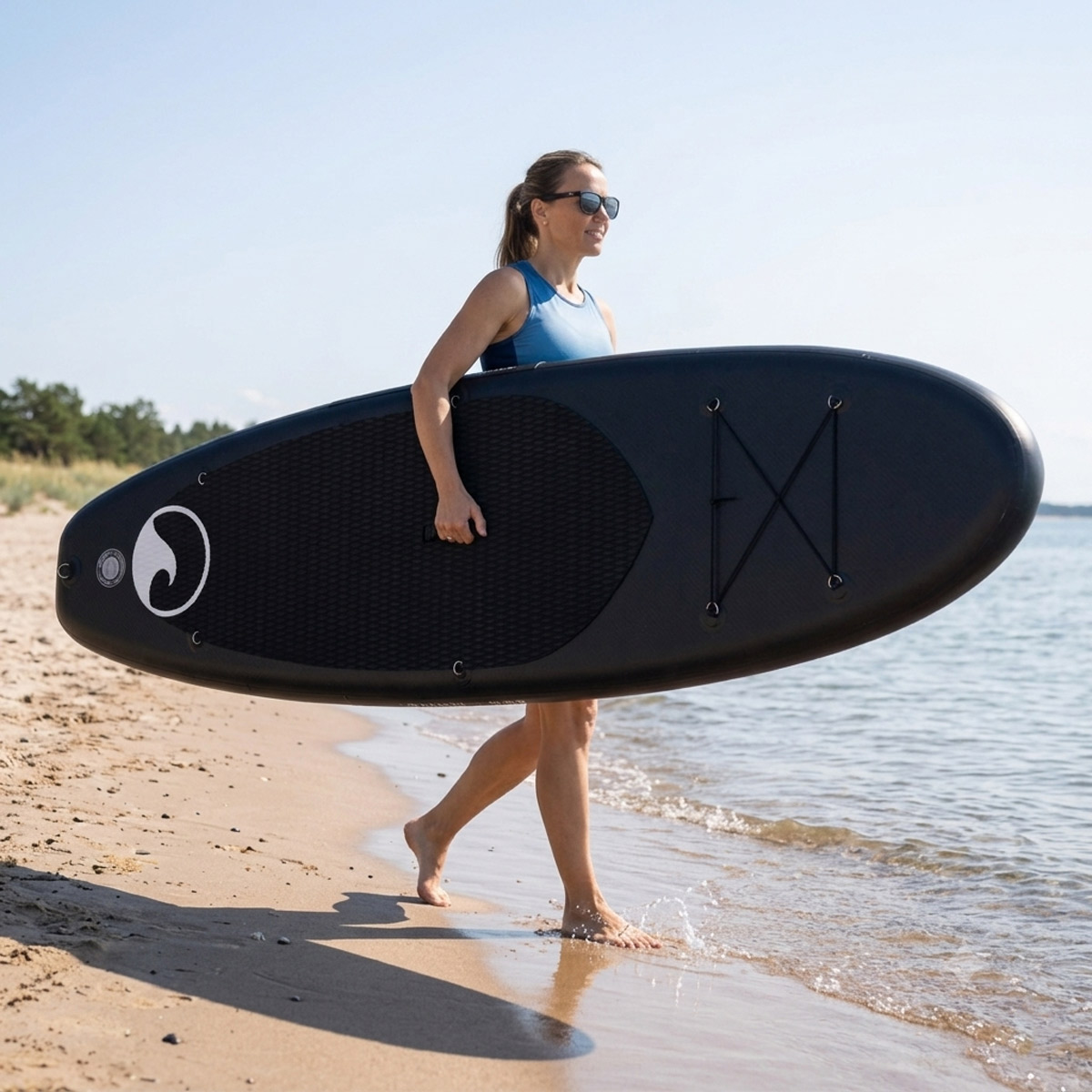 Kobieta spaceruje po plaży z deską surfingową
