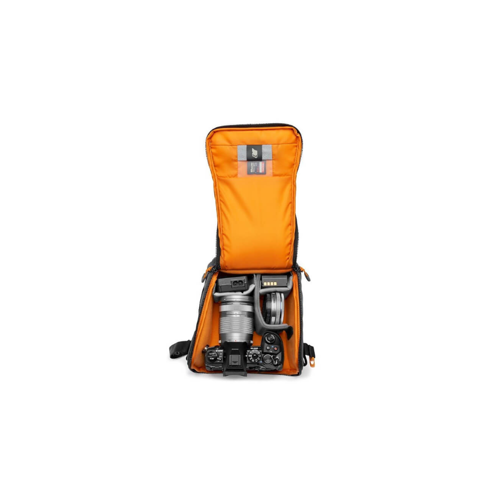 Offene Kameratasche mit orangefarbenem Innenfutter, Kamera, Objektiv und Akku.