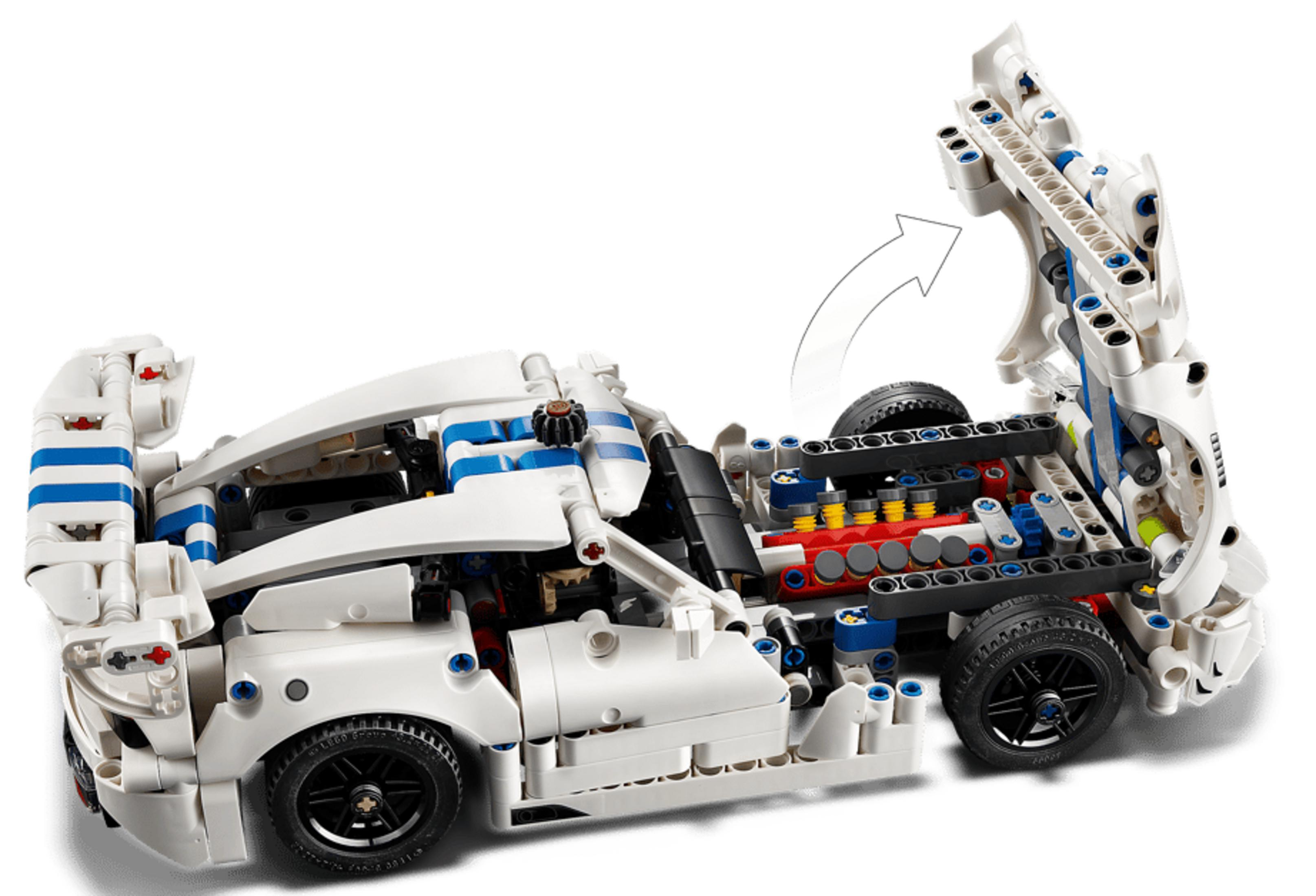 Motoru ortaya çıkaran açık kaputlu beyaz bir Lego araba.