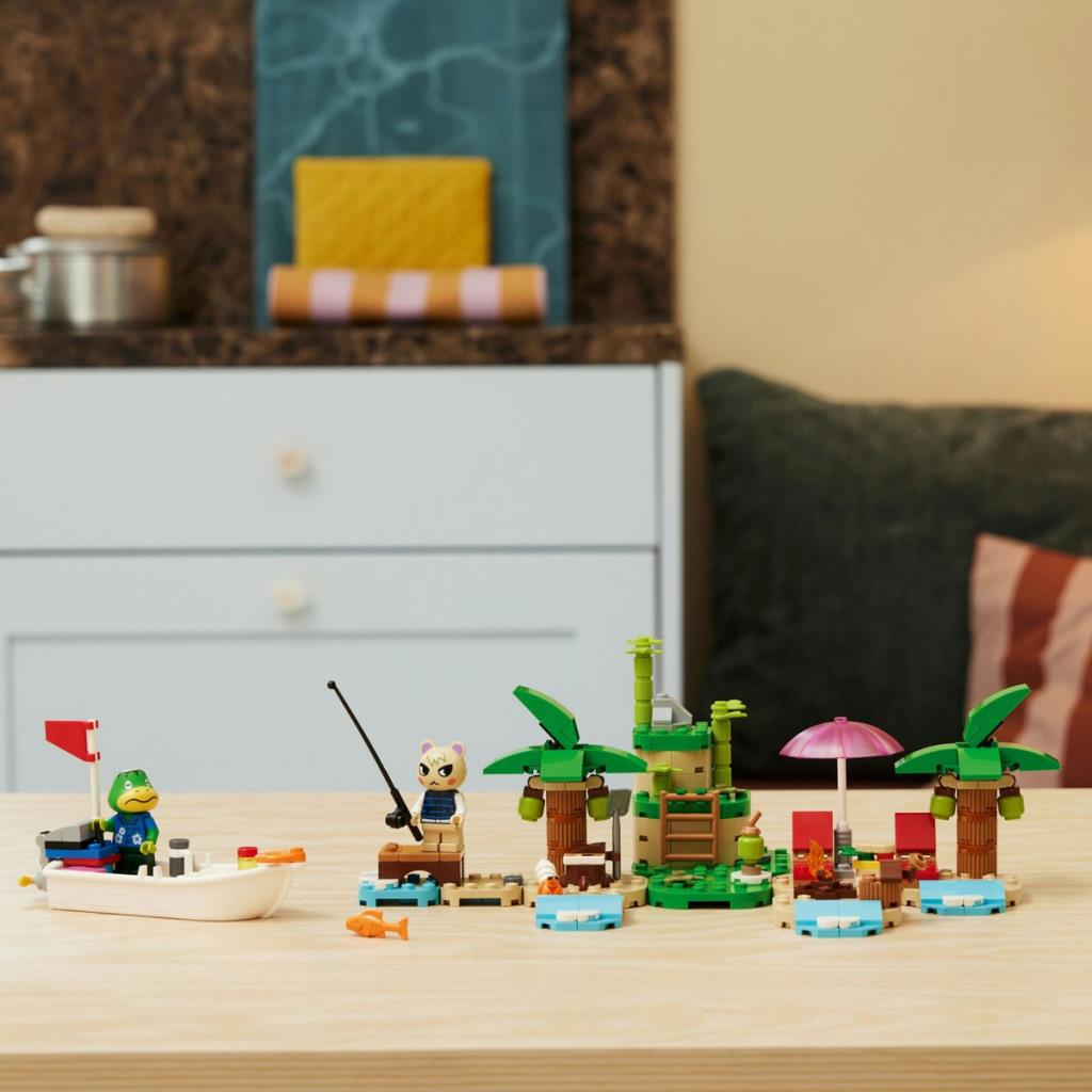 Figürler, tekne, palmiye ağaçları ve küçük kamp ateşi içeren Lego plaj sahnesi.