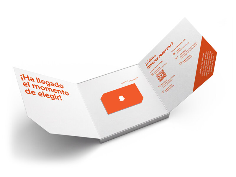 Una caja plegable blanca con texto naranja y una tarjeta naranja.