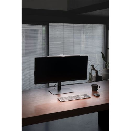 A dark desk with a monitor, keyboard, mouse, and mug.