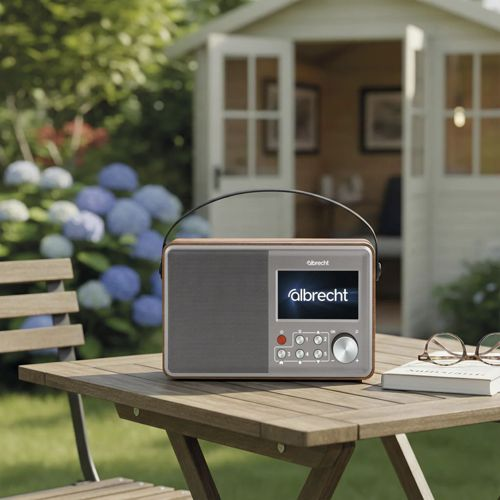 Una radio Albrecht su un tavolo da giardino in legno, con capanno e ortensie sullo sfondo.