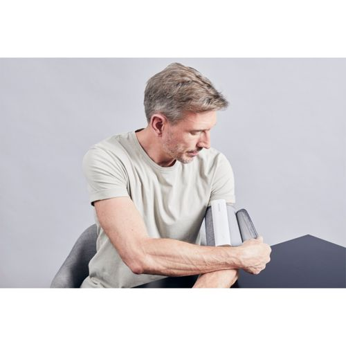 Mann sitzt am Tisch und hält drei graue Ordner in den Armen.