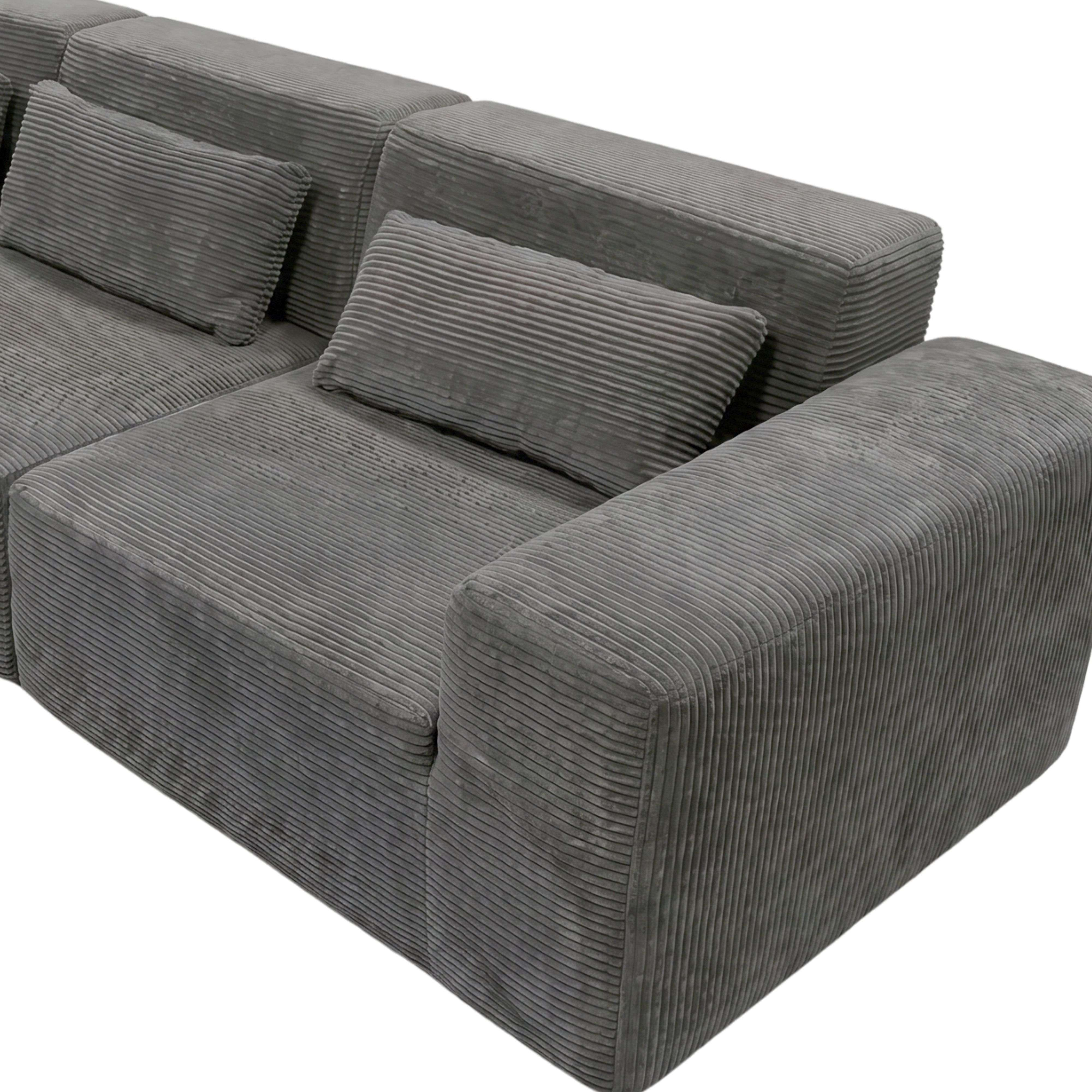Sofá gris de pana con textura acanalada y cojines.