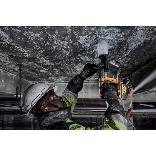 Un trabajador de la construcción con casco usa una pistola de clavos amarilla en un techo de hormigón.