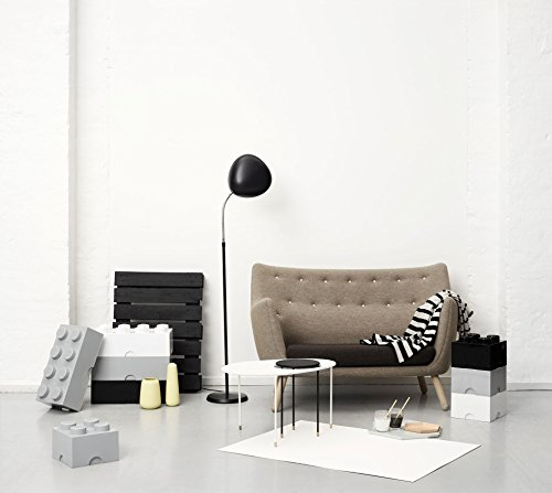 Un soggiorno moderno con divano grigio, lampada da terra nera e contenitori a mattoncini.