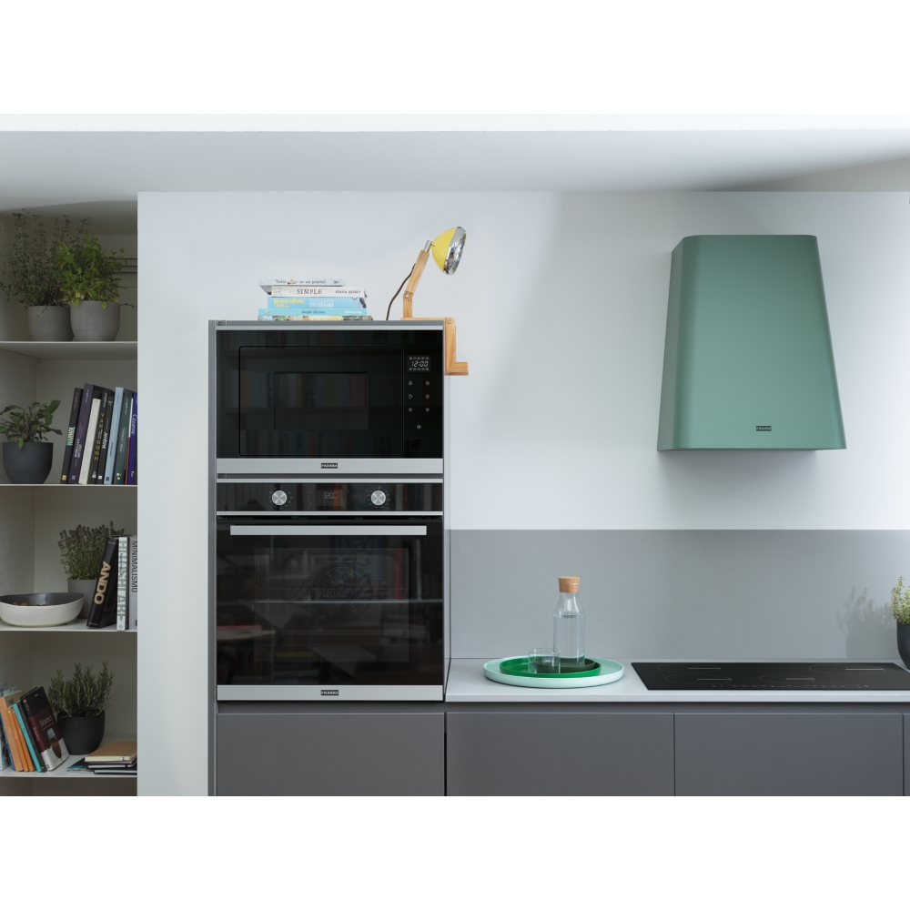 Cucina moderna con elettrodomestici integrati, cappa verde e libreria.