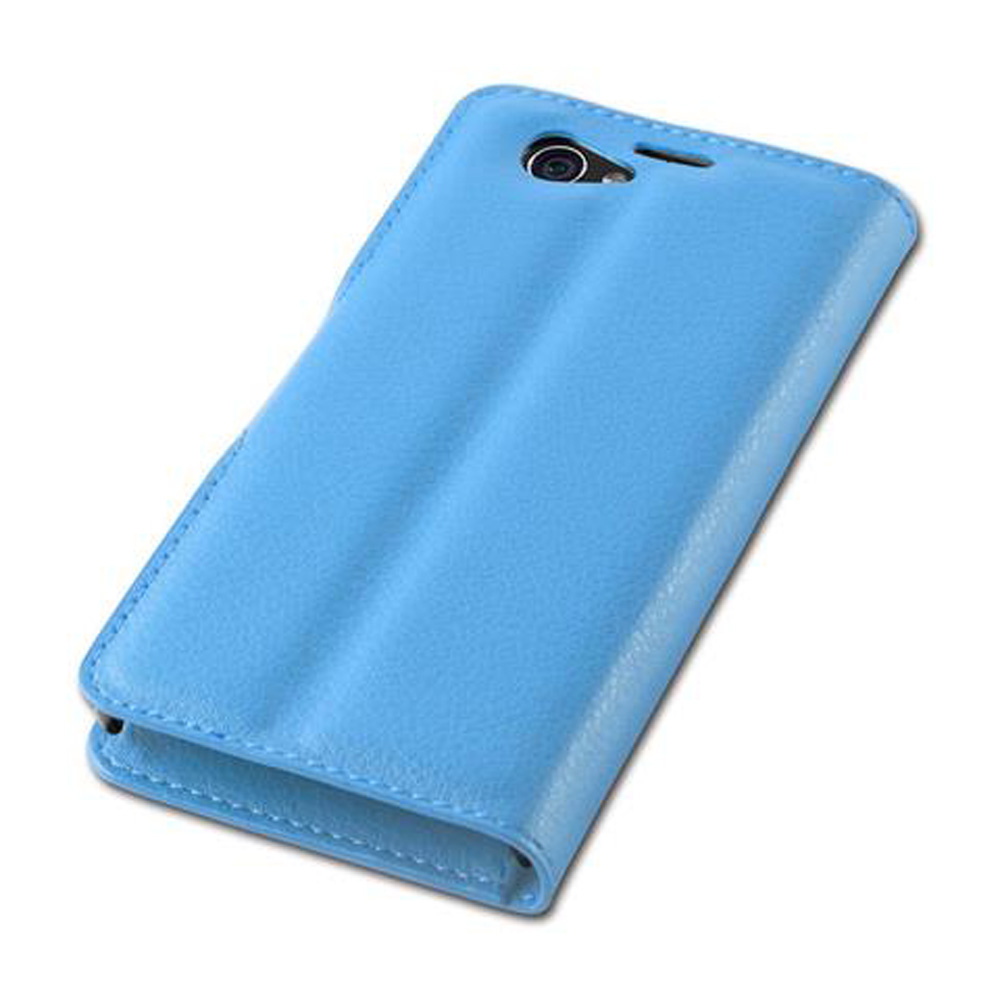 Una custodia per telefono in pelle azzurra chiusa con finitura testurizzata. È visibile un obiettivo della fotocamera.