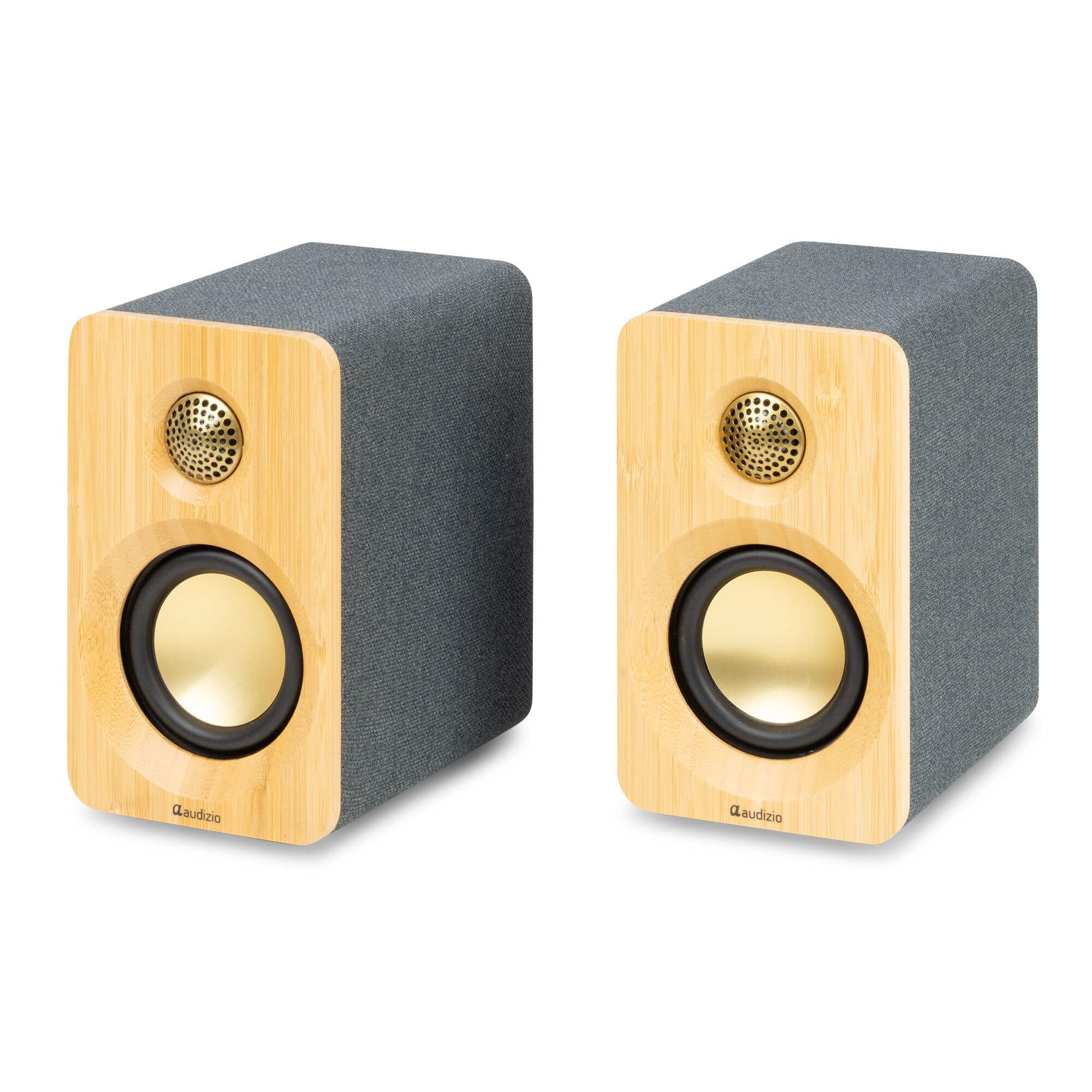 Dos altavoces grises con frentes de madera y conos dorados, uno al lado del otro.