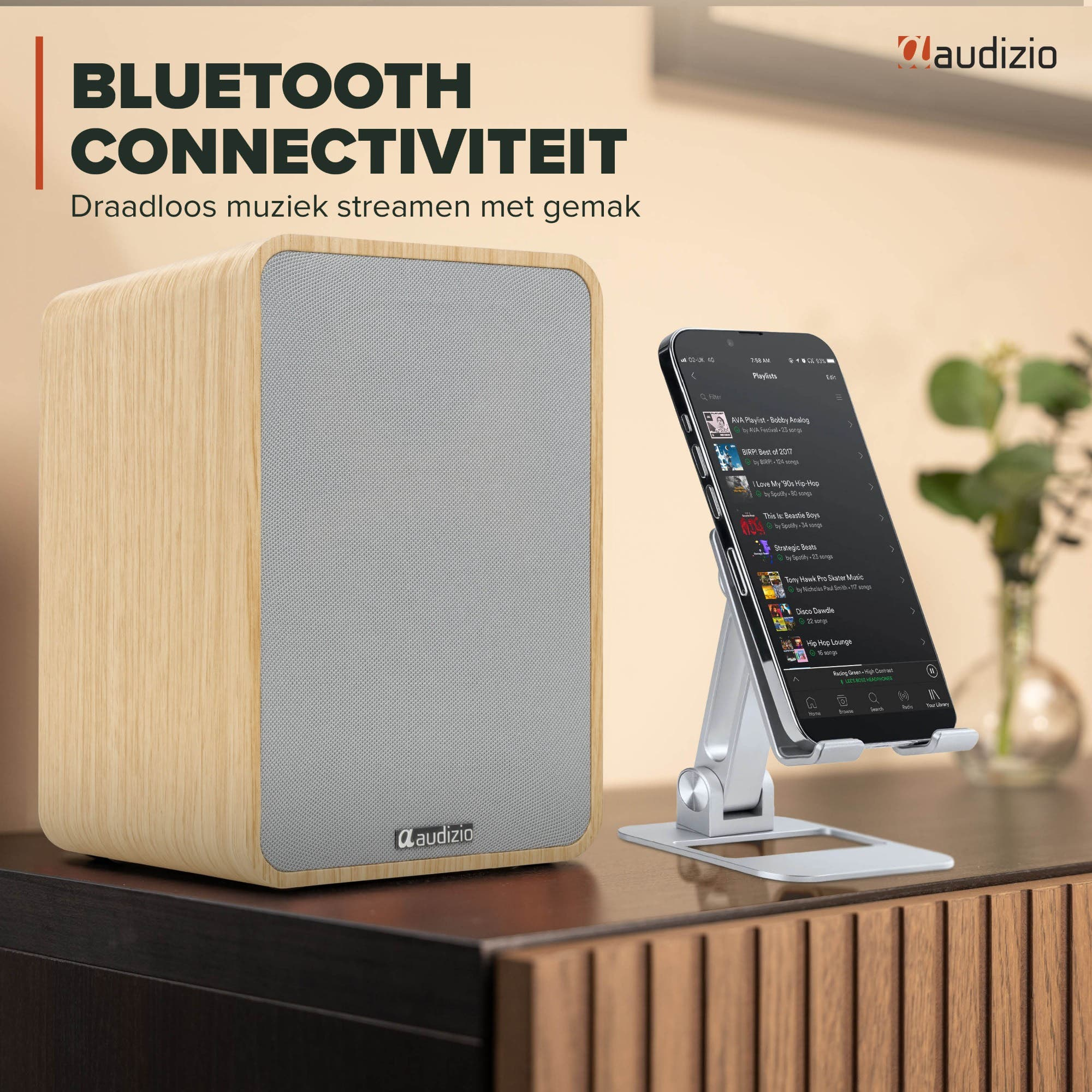 Altavoz de madera junto a un smartphone que muestra listas de música.