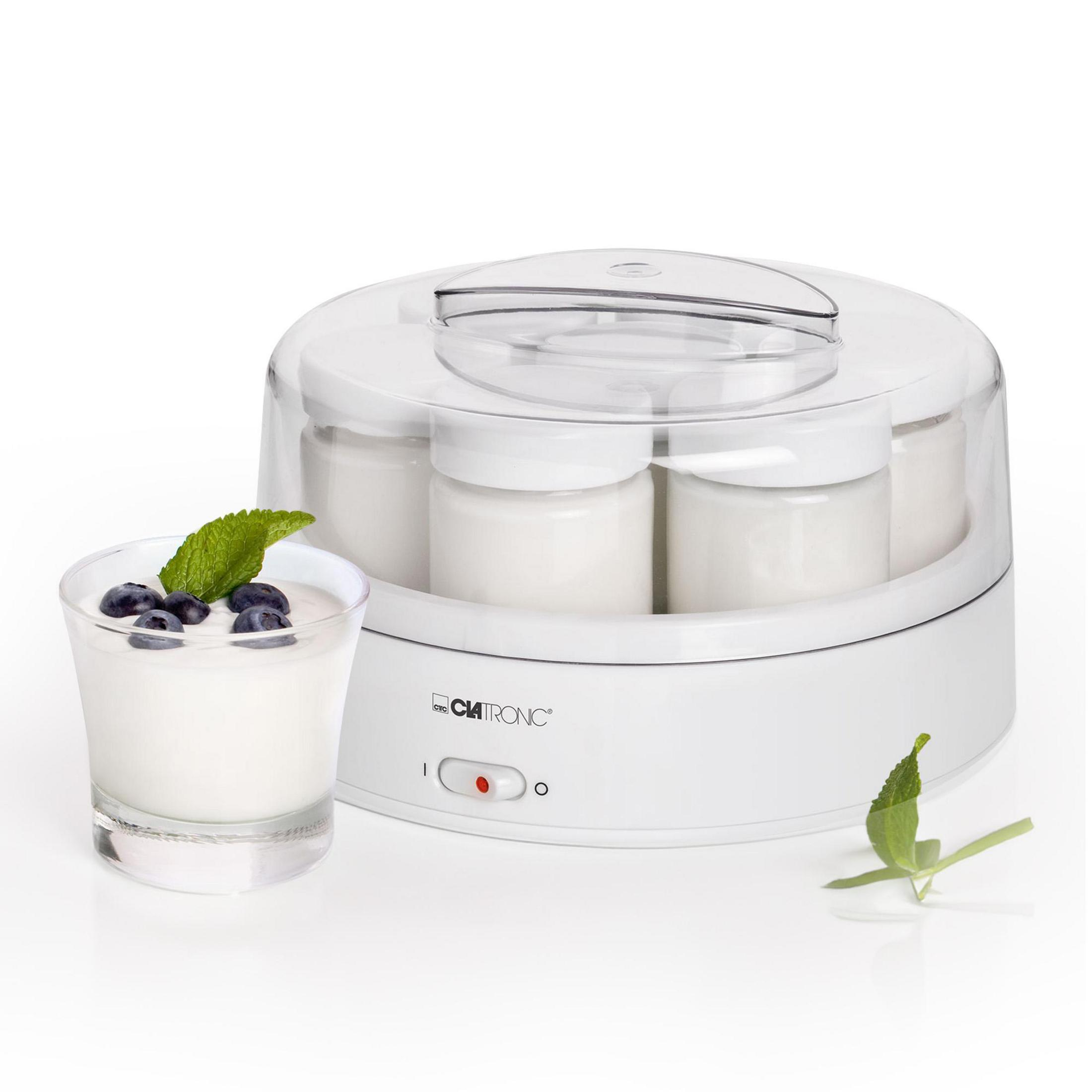 Ein weißer Joghurtbereiter mit sechs Gläsern und einem Glas Joghurt mit Beeren und Minze.