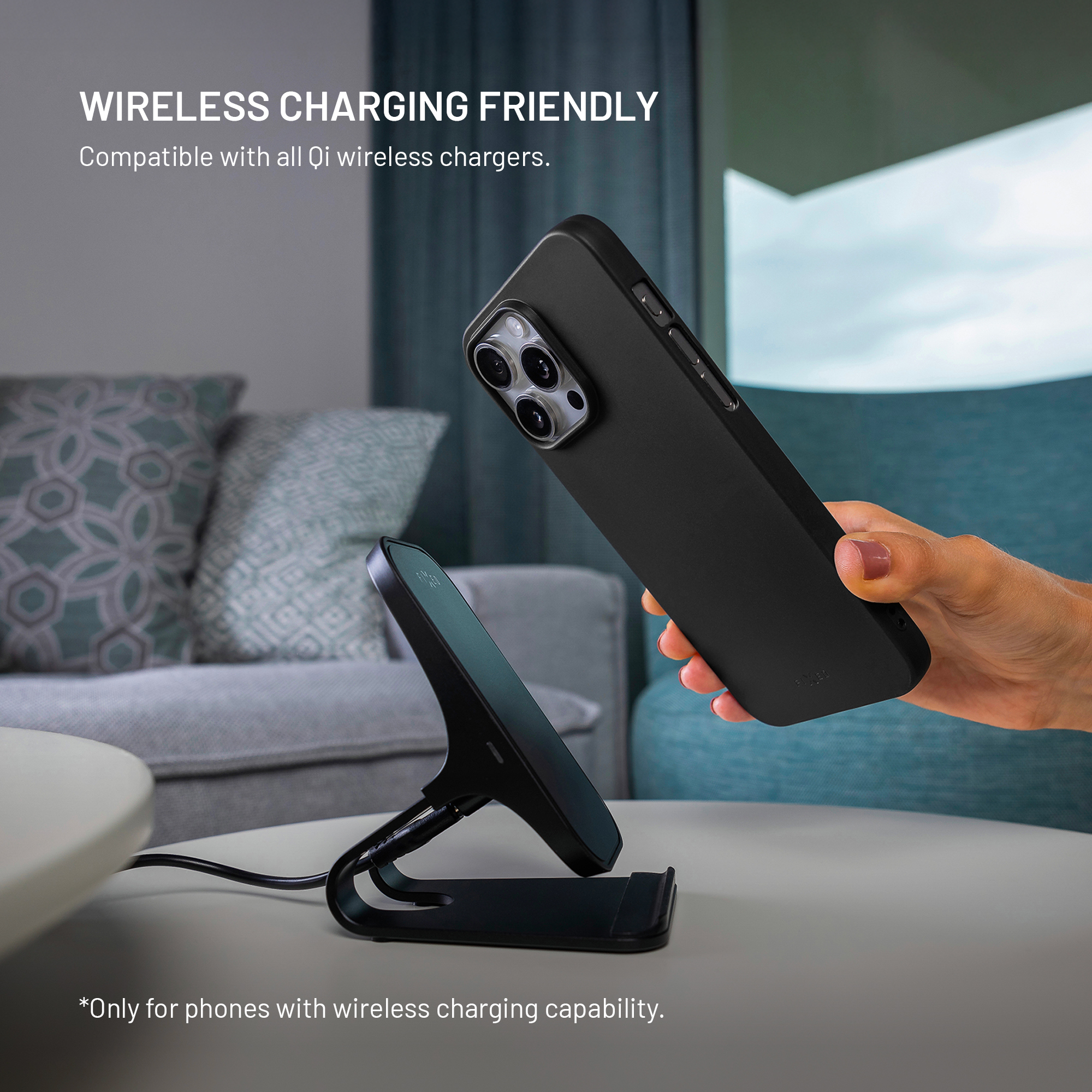 Schwarzes Handy mit Kamera wird über ein Ladekabel an eine kabellose Ladestation gehalten.