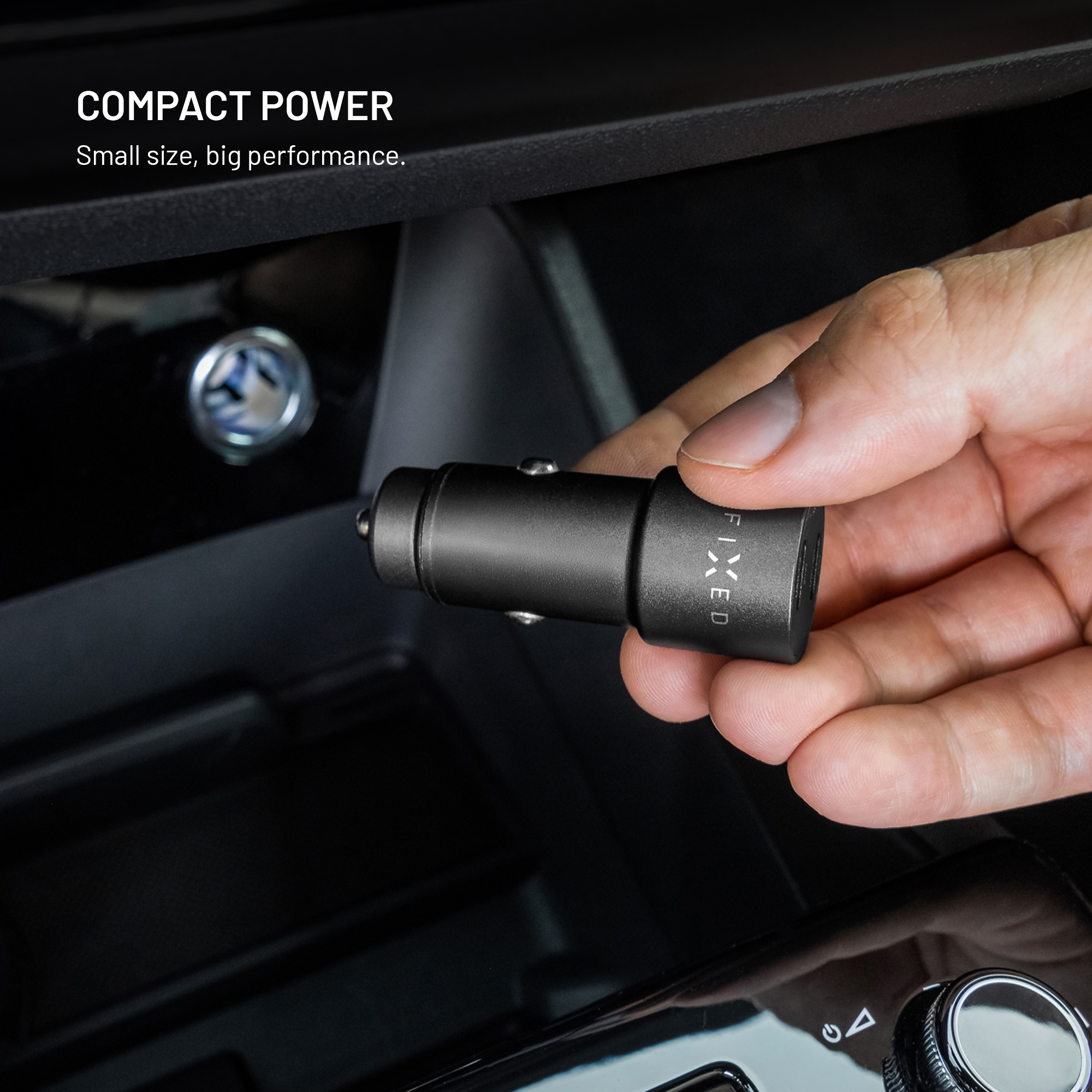 Eine Hand hält einen schwarzen Auto-Adapter mit der Aufschrift FIXED.