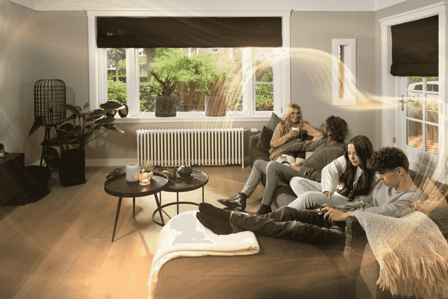 Cuatro personas se relajan en un sofá en una acogedora sala de estar con vistas a un jardín.