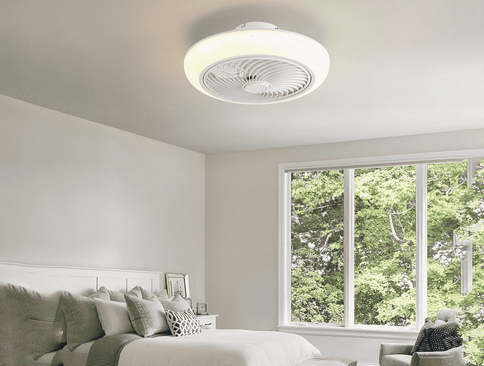 Un ventilador de techo moderno con luz sobre una cama con cojines y una gran ventana.