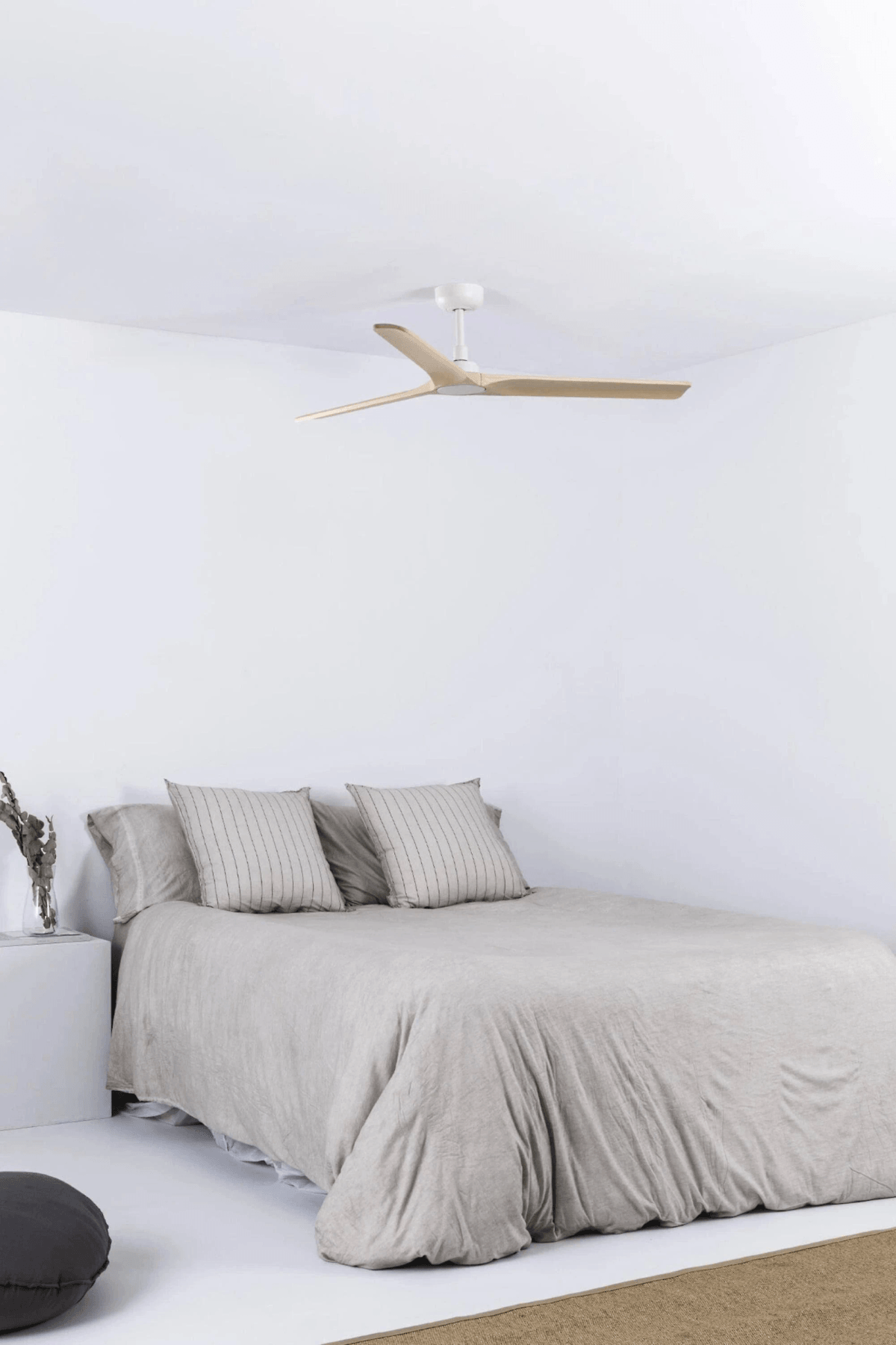 Ein Schlafzimmer mit einem Bett, Deckenventilator und Nachttisch.