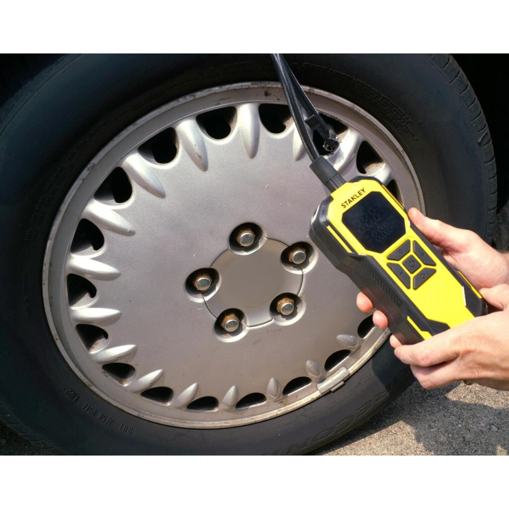 Un manometro digitale giallo e nero misura uno pneumatico per auto.