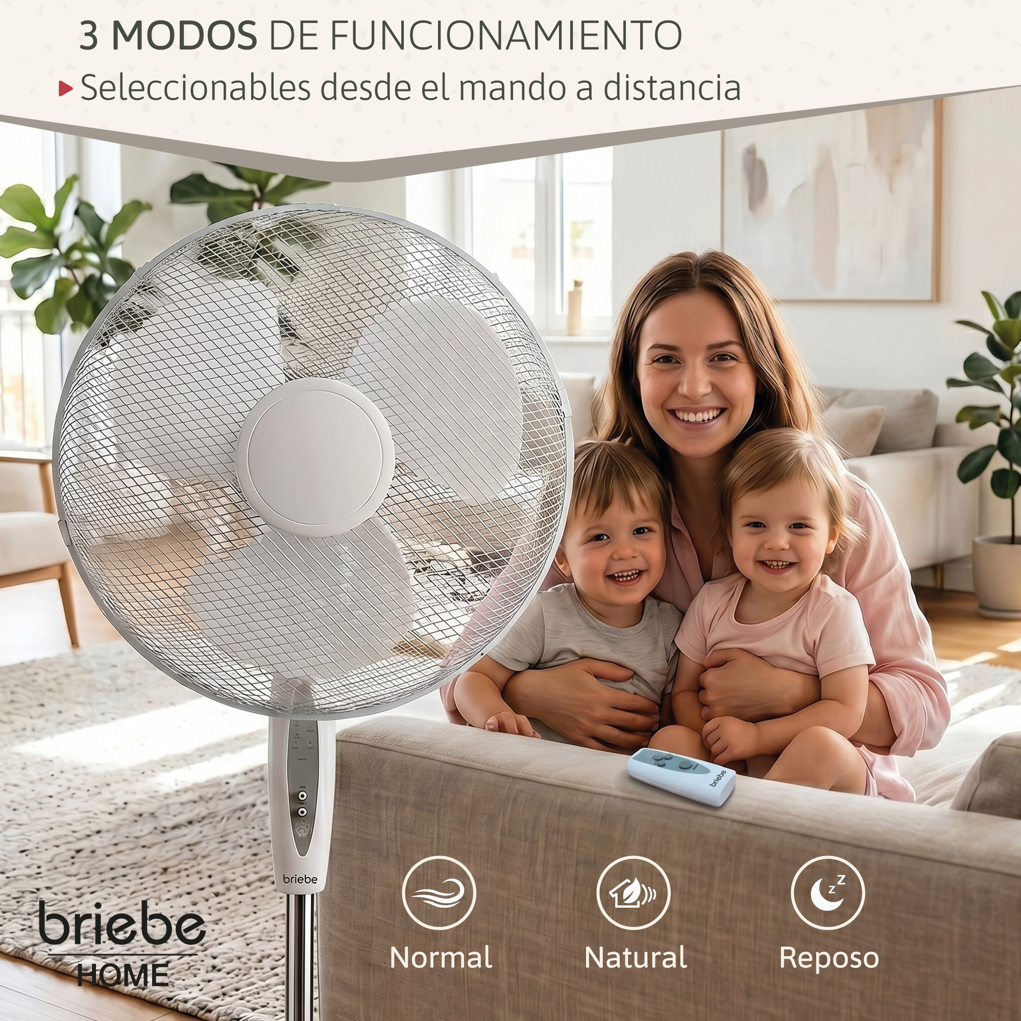 Una mujer sonríe sosteniendo a dos niños pequeños frente a un ventilador y un sofá.