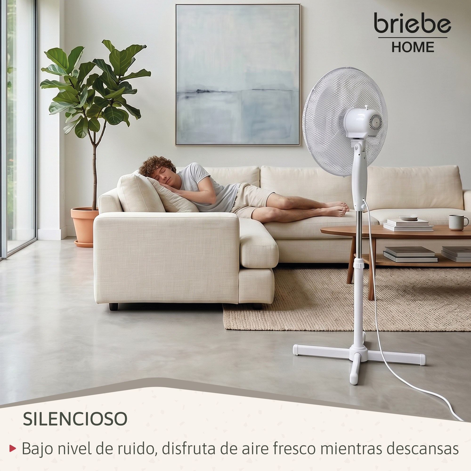 Un hombre duerme en un sofá, con un ventilador cerca.