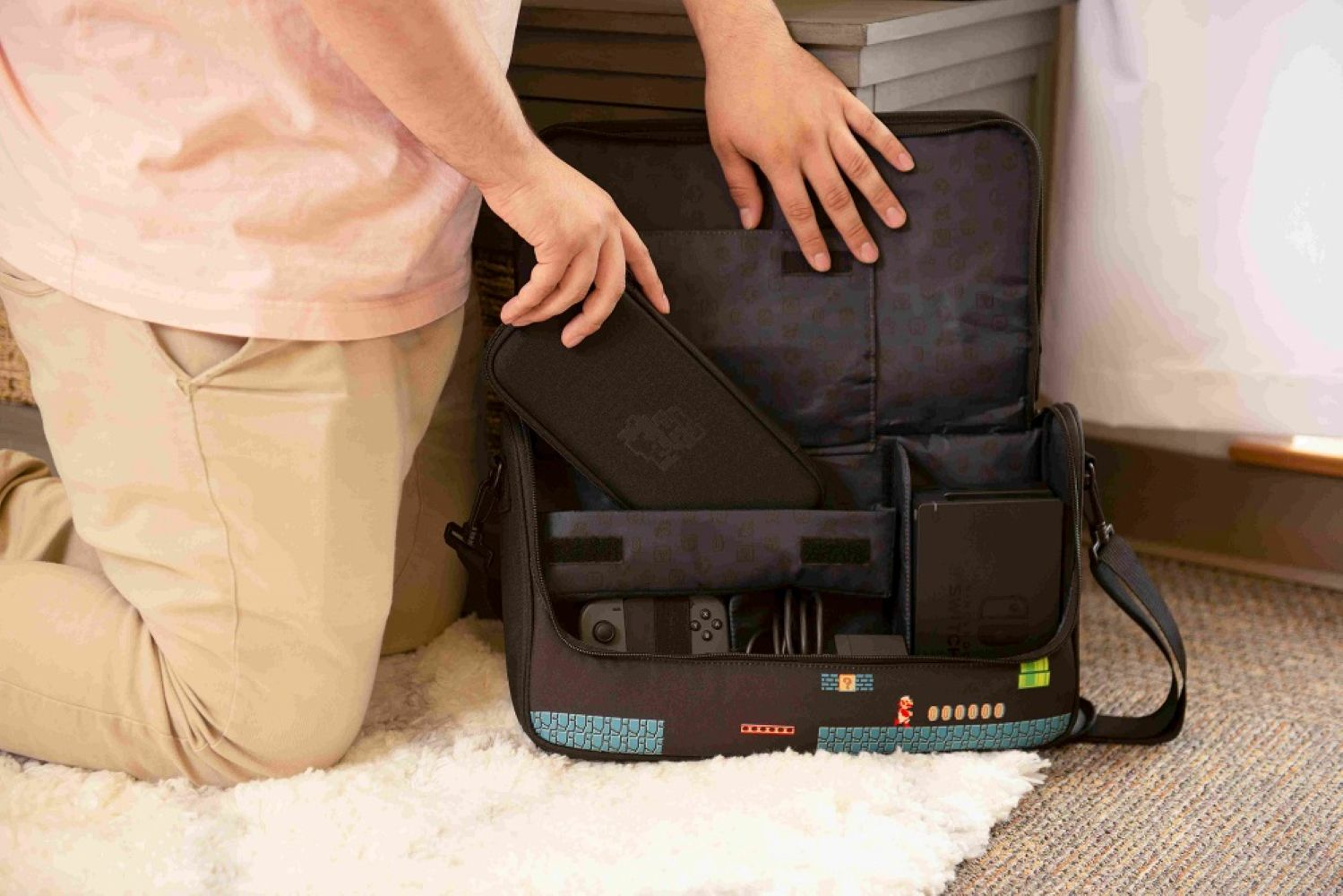 Mani posizionano custodia in borsa a tema Mario con console Switch, controller e cavi.
