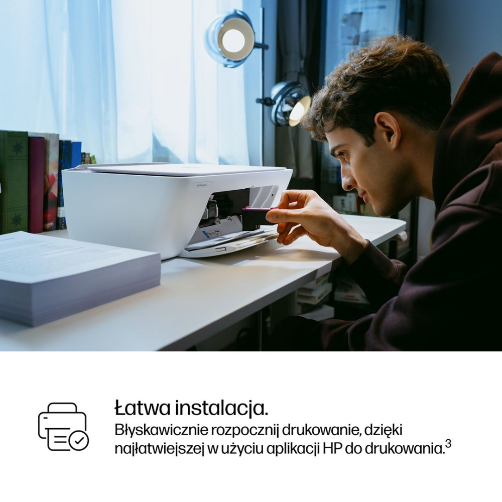 Mężczyzna wkłada fioletowy tusz do białej drukarki.