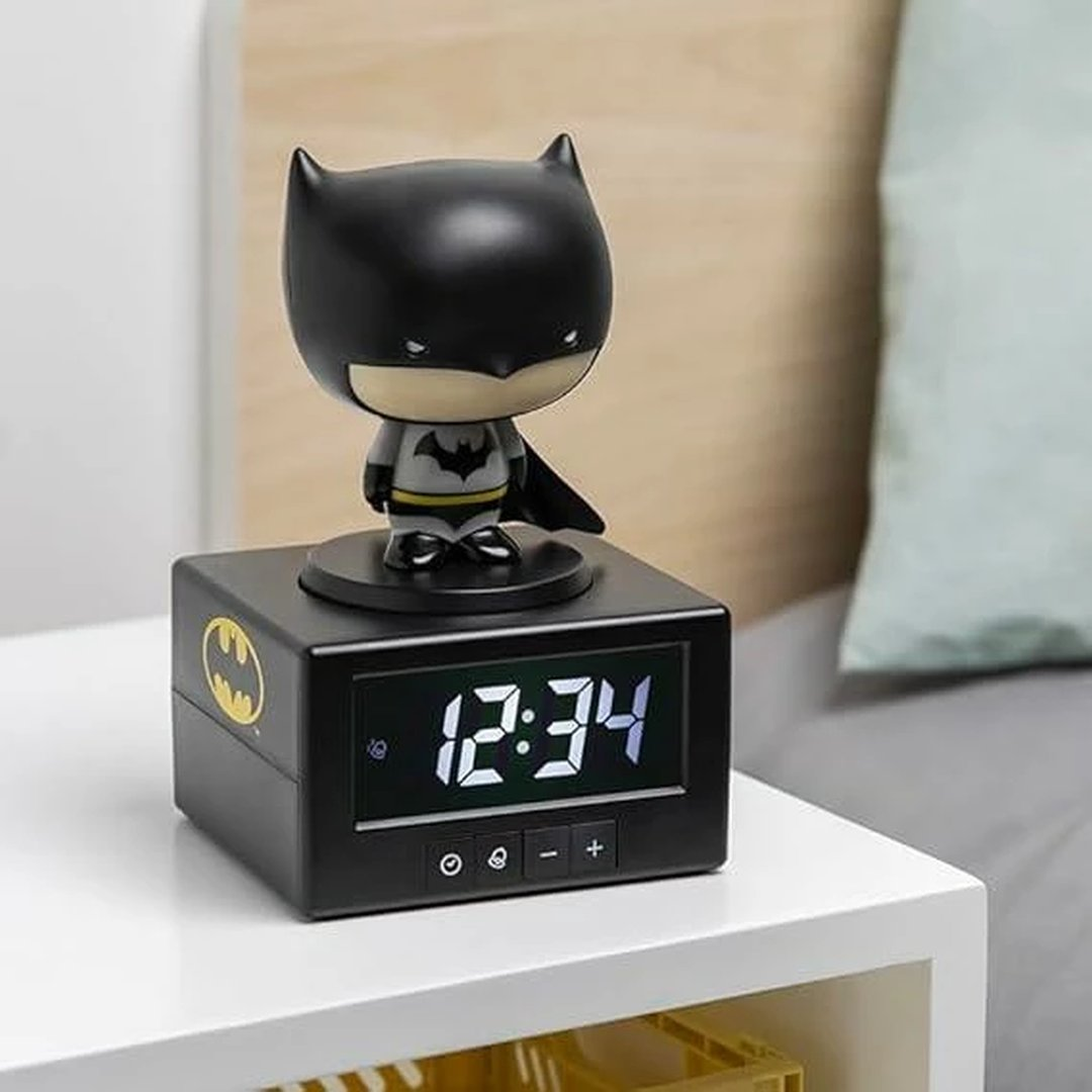 Budzik Batmana z cyfrowym wyświetlaczem i figurką na stoliku nocnym.