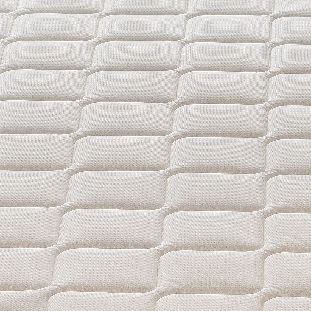 Una vista de cerca de un colchón blanco con un patrón acolchado.