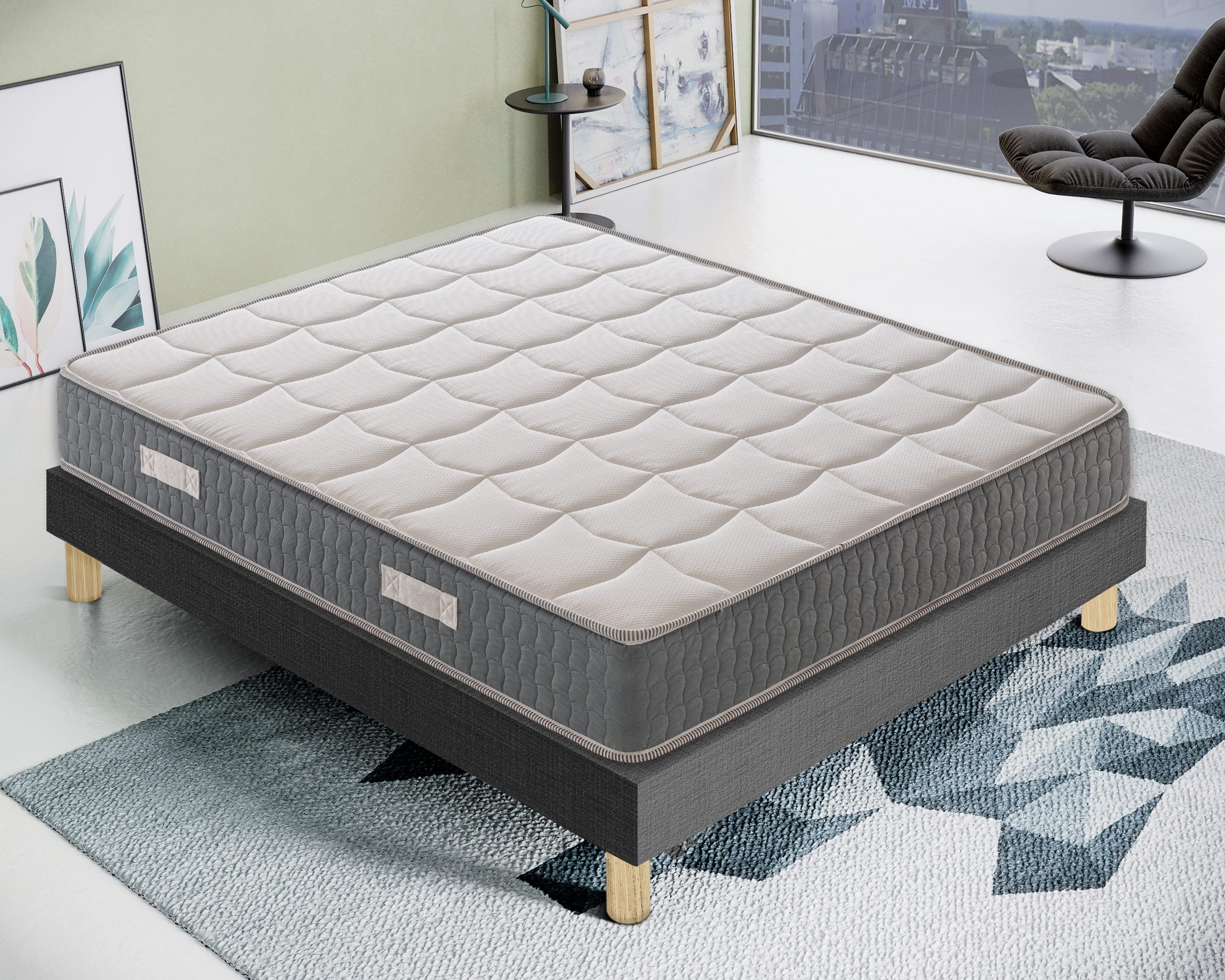 Una cama gris con colchón blanco sobre una alfombra.