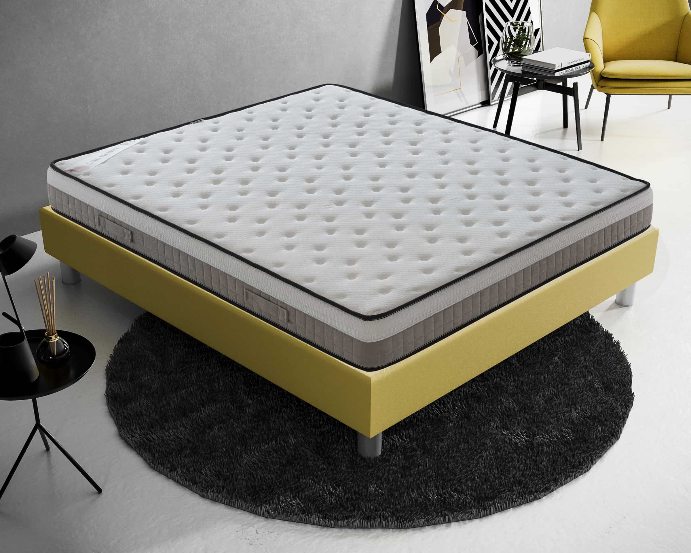Un colchón blanco sobre un somier amarillo con alfombra negra y decoración moderna.