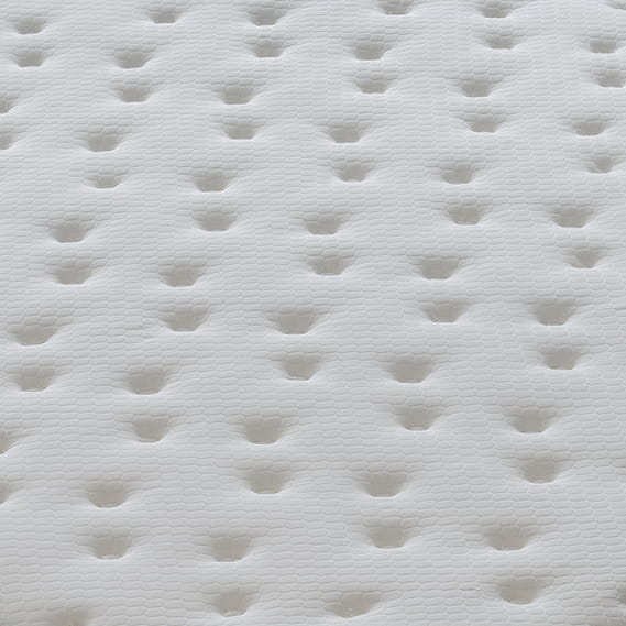 Superficie acolchada blanca con patrones en relieve, mostrando espuma o textura de colchón.