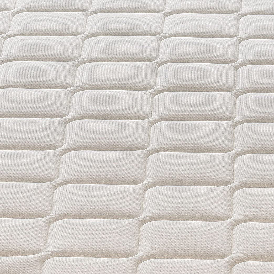Primer plano de un colchón blanco acolchado con textura visible.