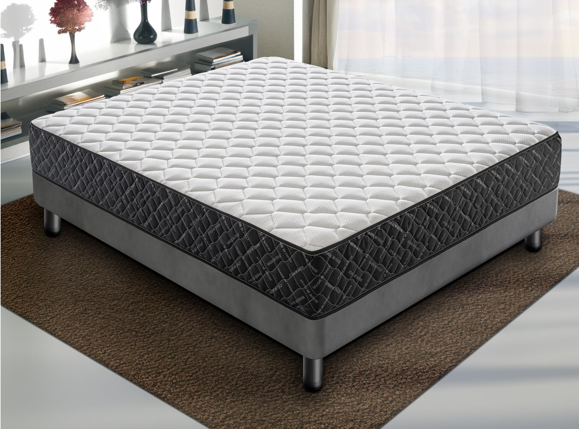 Una cama blanca y gris con colchón acolchado sobre una alfombra marrón.