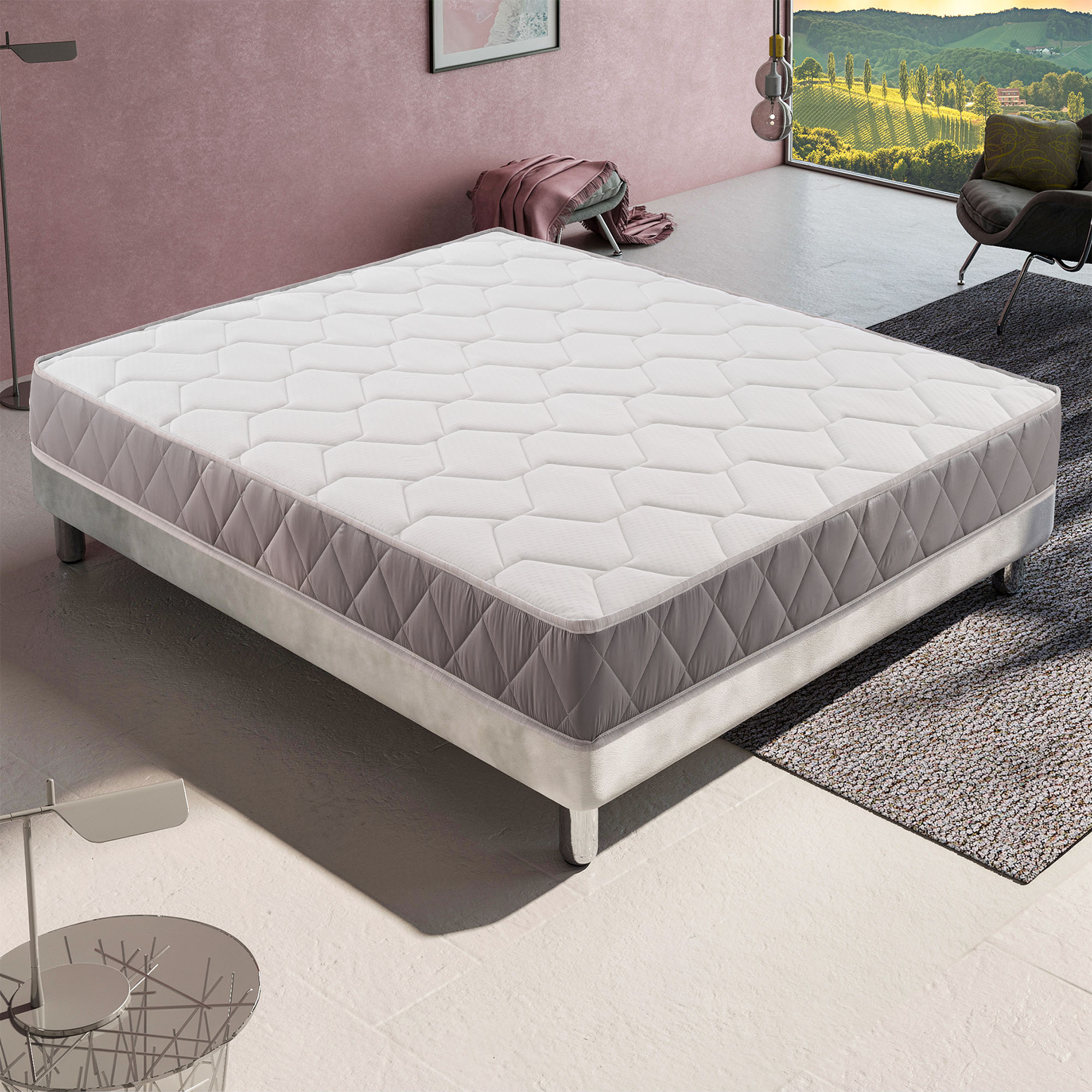 Una cama con colchón blanco y borde gris está en una habitación con ventanal.