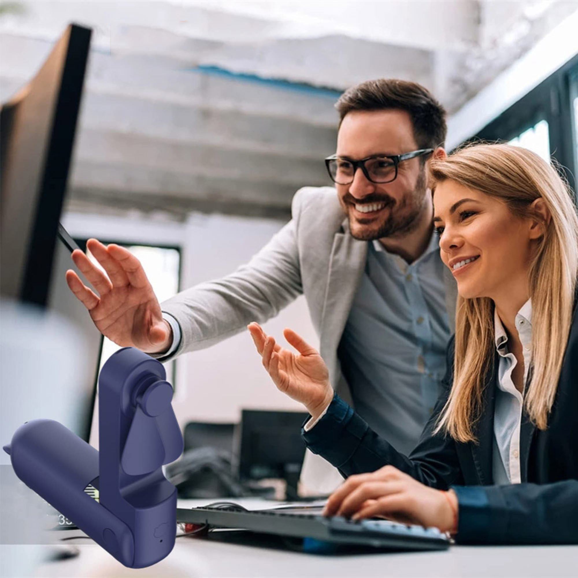Ein Mann und eine Frau arbeiten am Computer, ein blauer Lüfter liegt vorne.