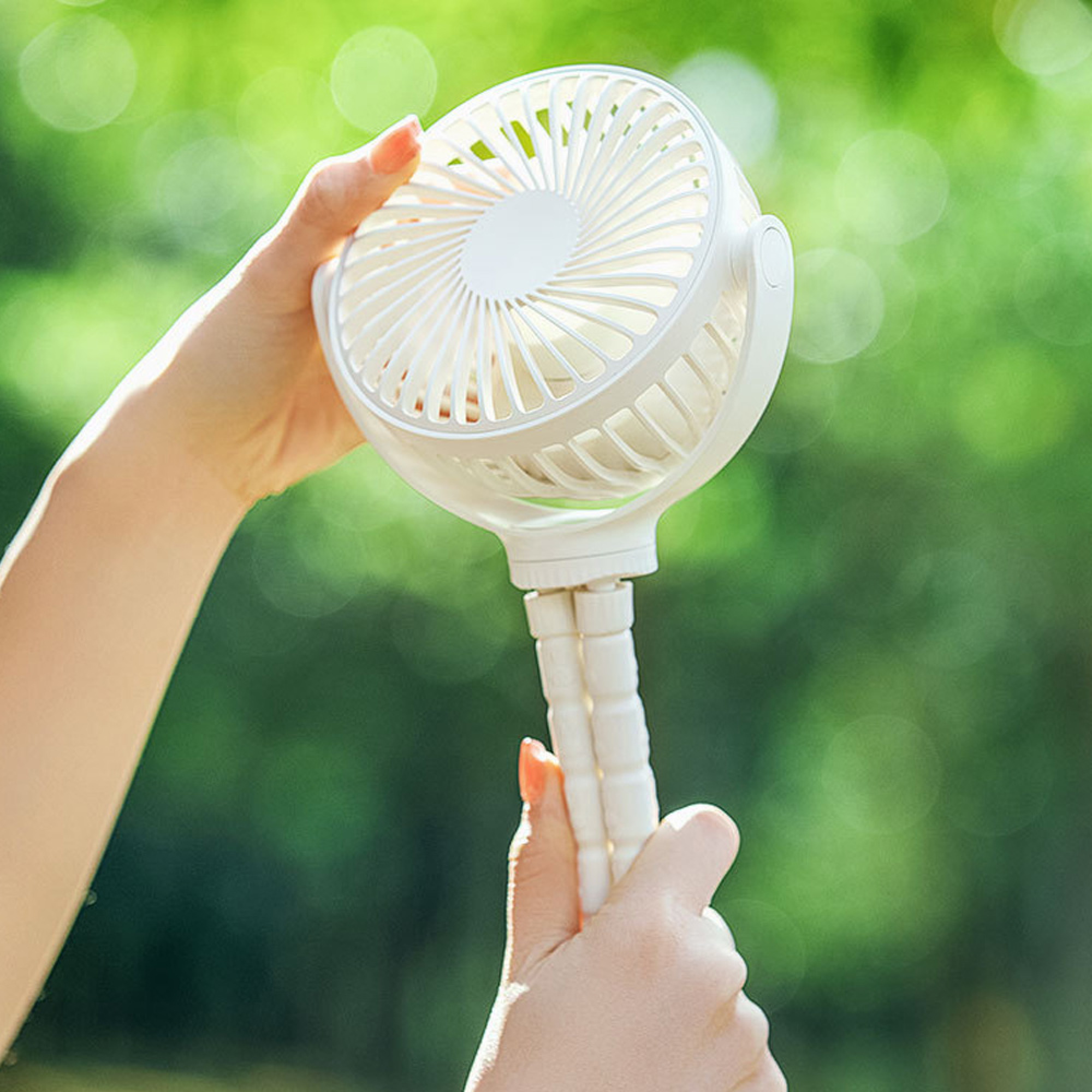 Eine weiße Hand hält einen kleinen, weißen Ventilator mit einem flexiblen Griff.