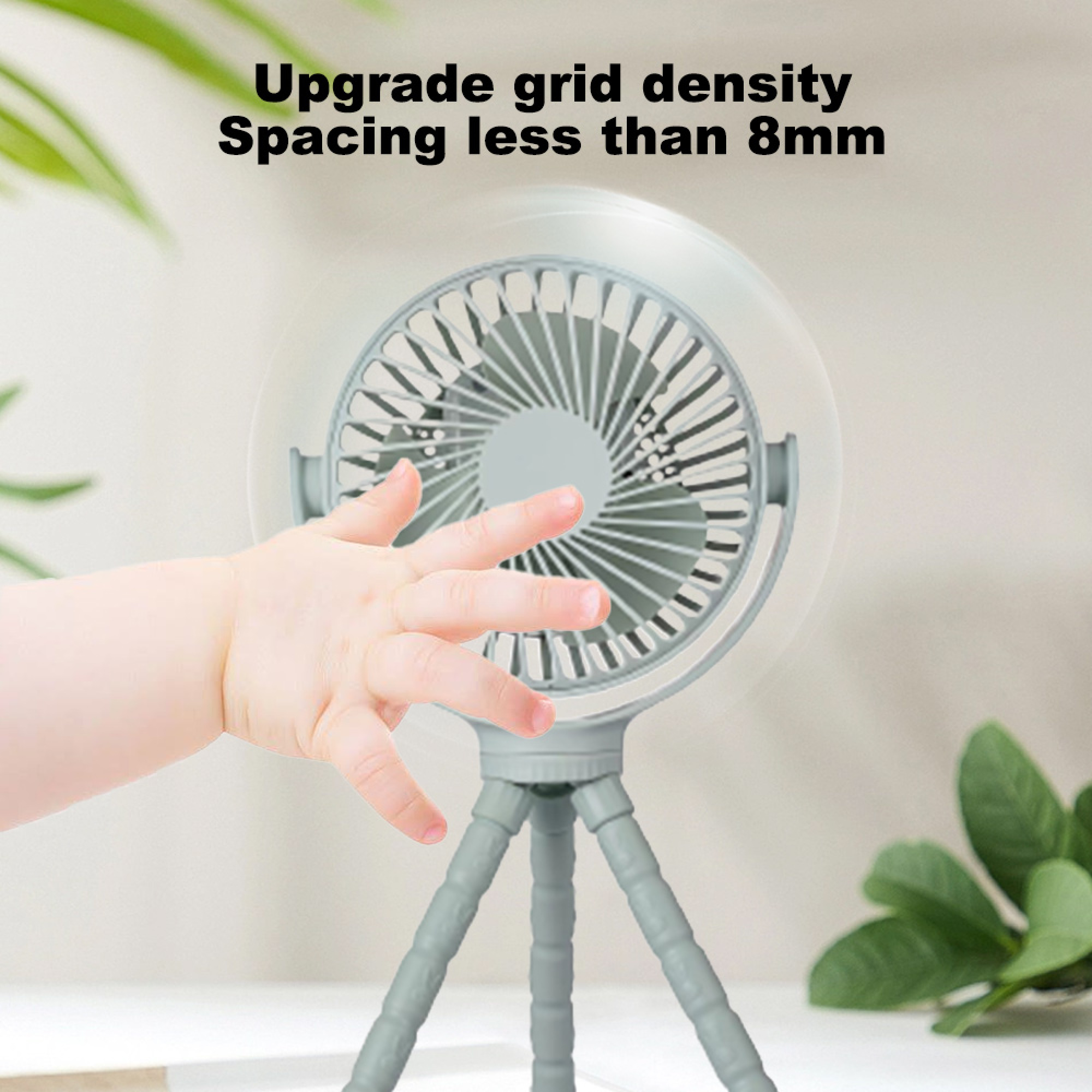 Ein Babyfinger nähert sich einem kleinen grauen Ventilator auf einem Stativ.