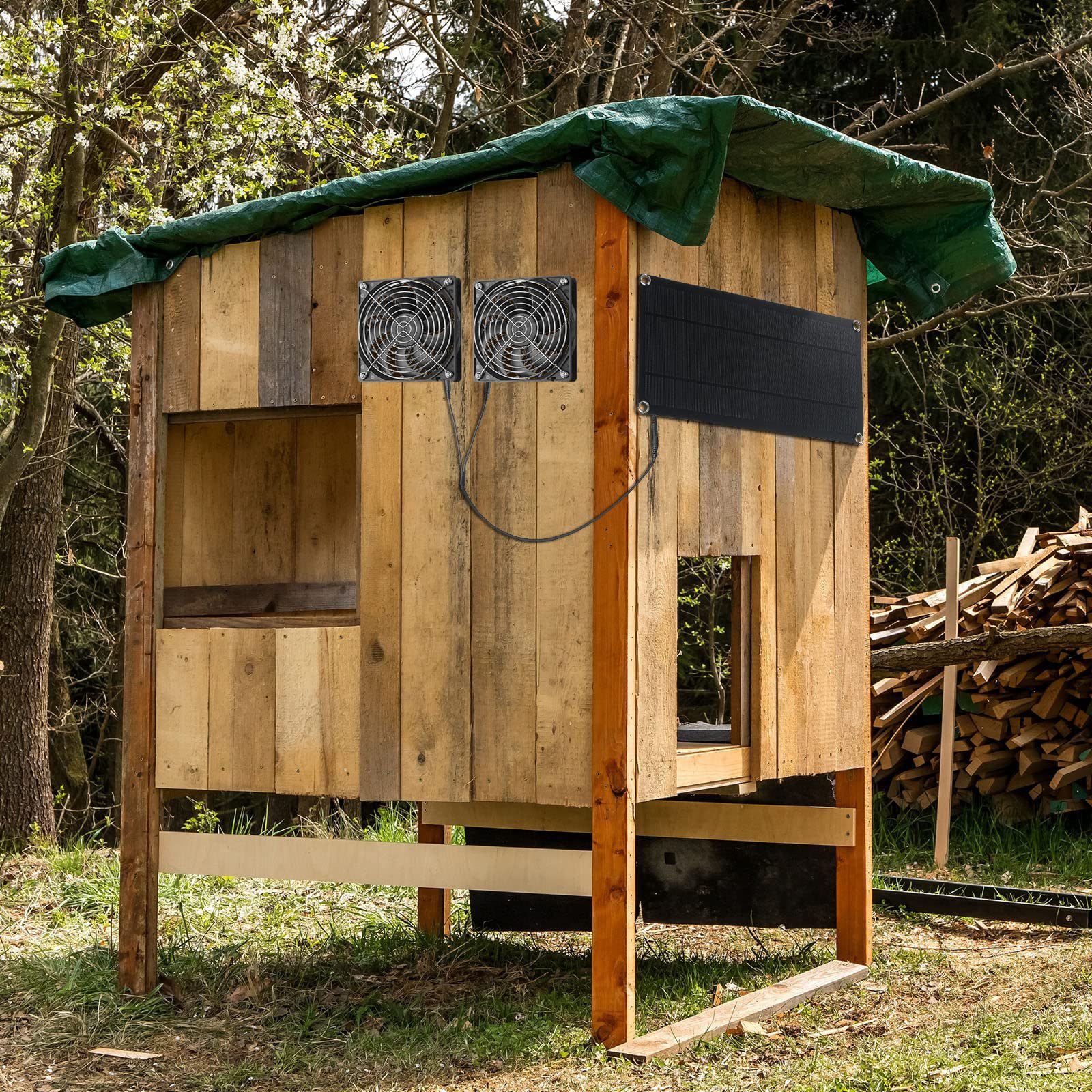Holzhütte mit Lüftern, Solarpanel und grünem Planendach im Freien.