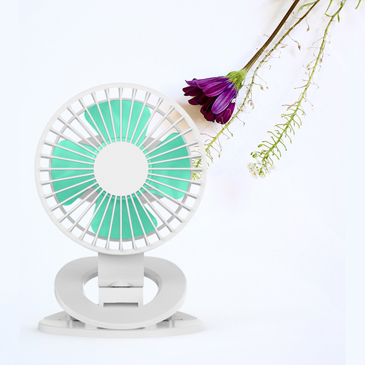 Ein weißer Ventilator mit türkisfarbenen Flügeln steht neben einer lila Blüte.