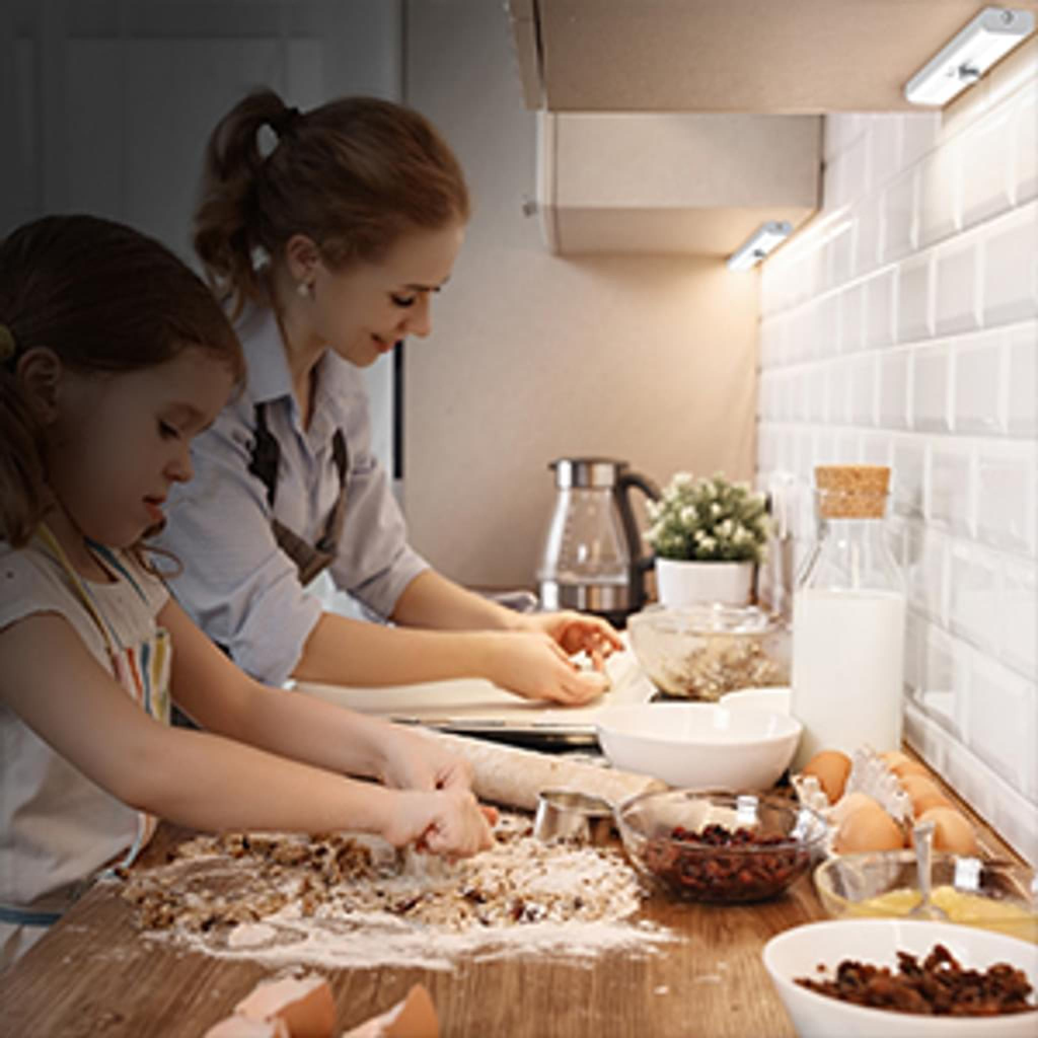 Mutter und Tochter backen zusammen in der Küche. Mehl und Zutaten sind auf dem Tisch.