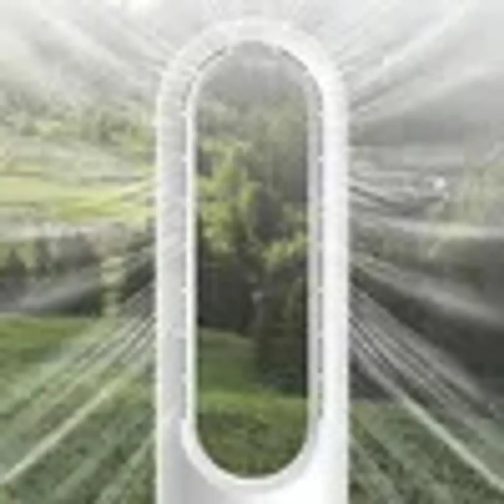 Ein weißer Turmventilator steht vor einer grünen Landschaft mit Bäumen.