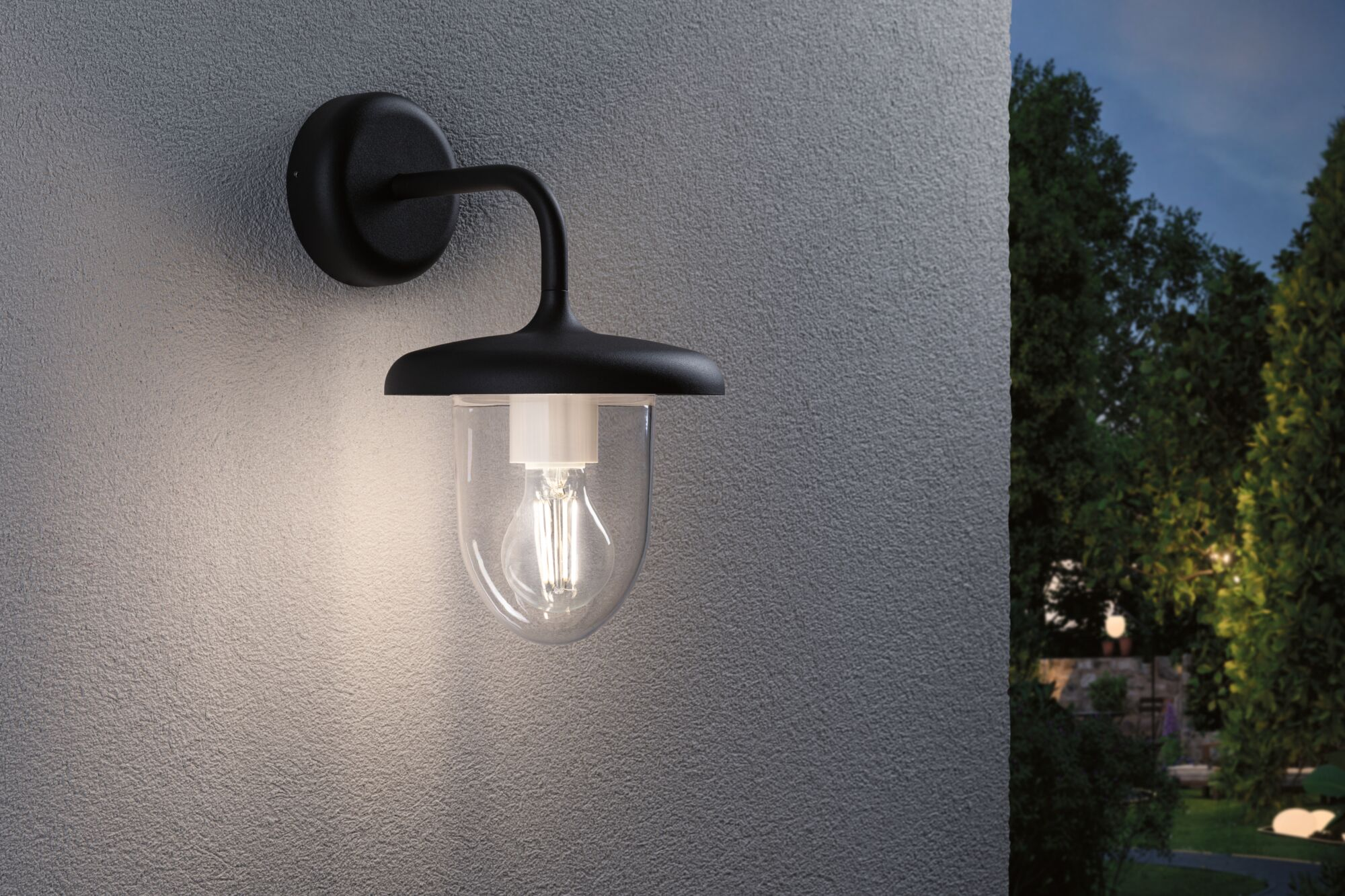 Schwarze Wandleuchte mit Glaskolben und Glühbirne an einer strukturierten Wand.
