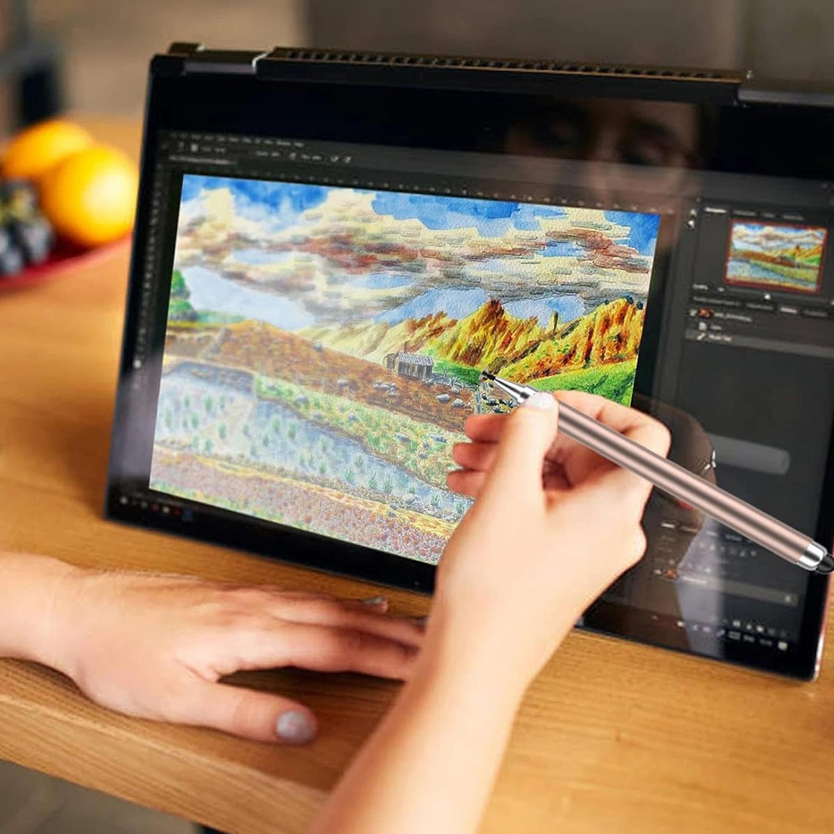 Eine Hand benutzt einen Stift auf einem Tablet, das eine Landschaftsmalerei zeigt.