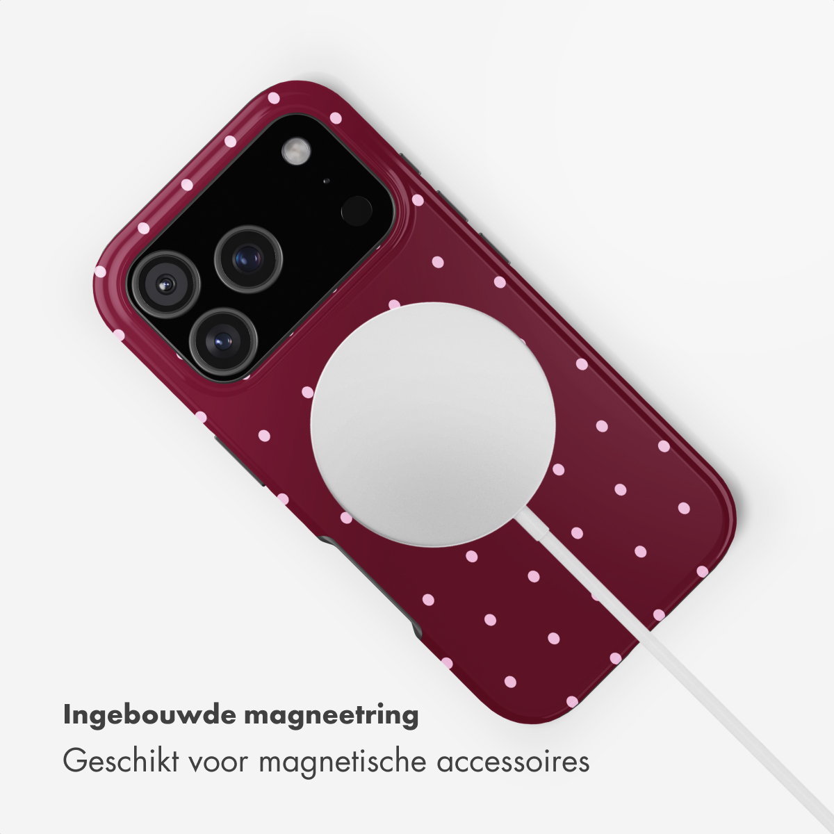 A burgundy phone case with pink polka dots and a white magnetic ring.