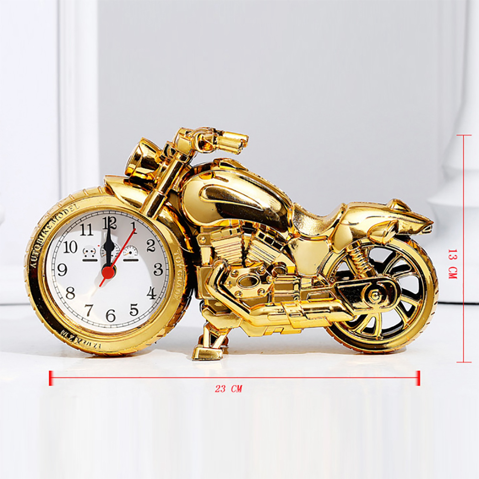 Goldene Motorraduhr mit weißen Zifferblatt und roten Zeigern.