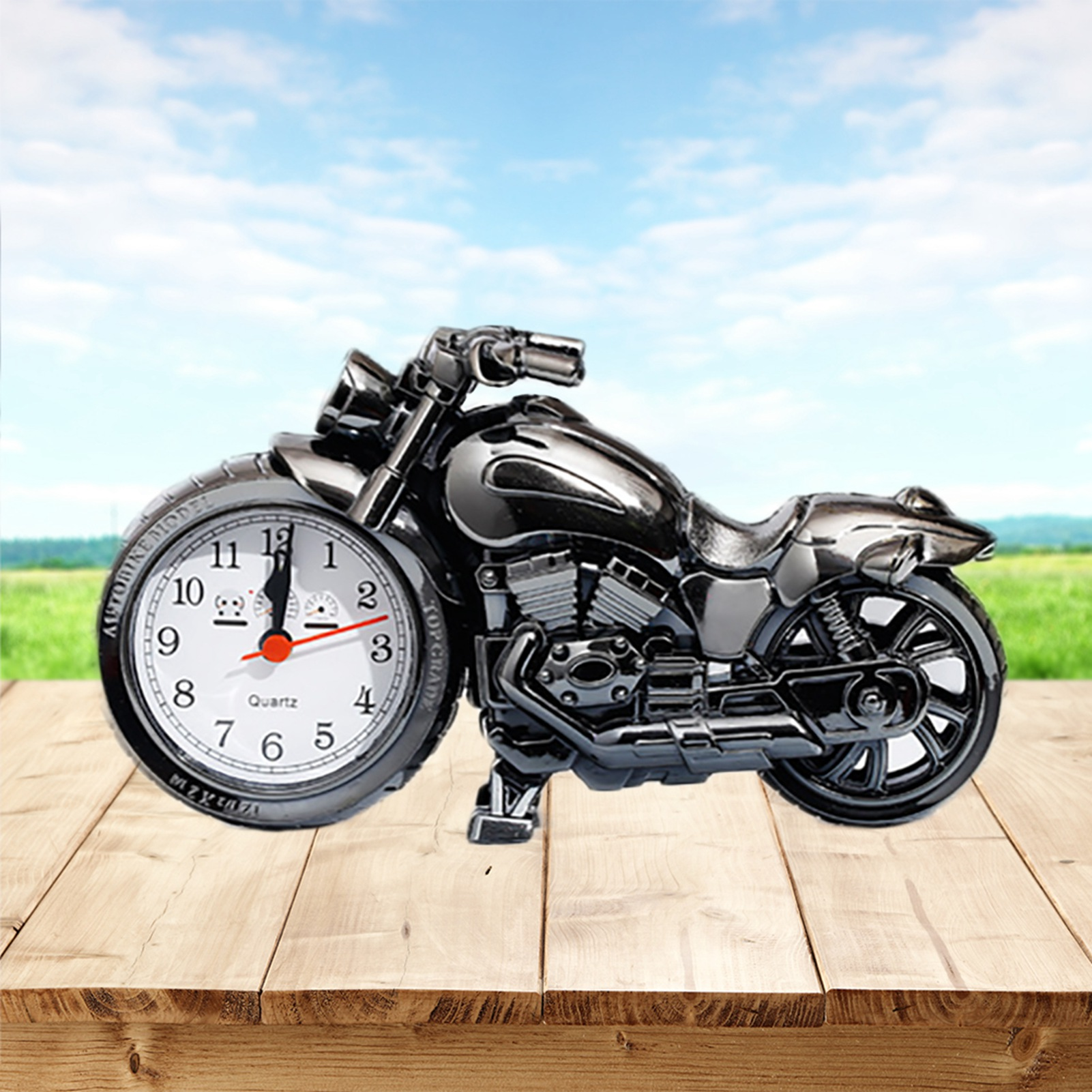 Ein schwarzer Motorrad-Wecker auf einem Holztisch vor blauem Himmel.